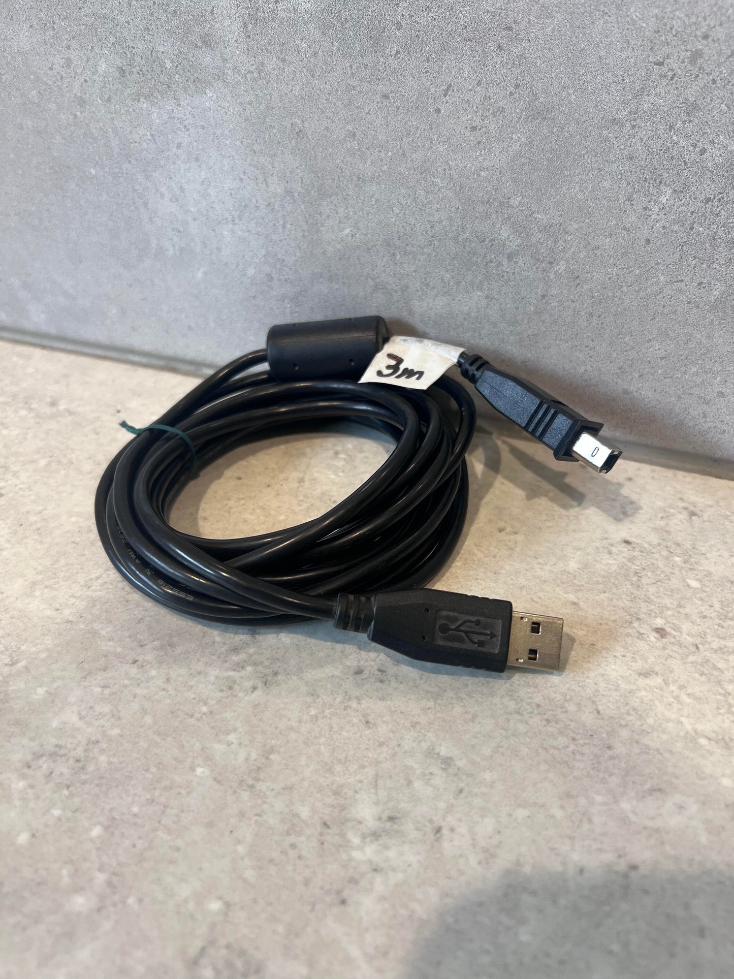 Coiled 3 meter USB to Mini USB cable on a light surface