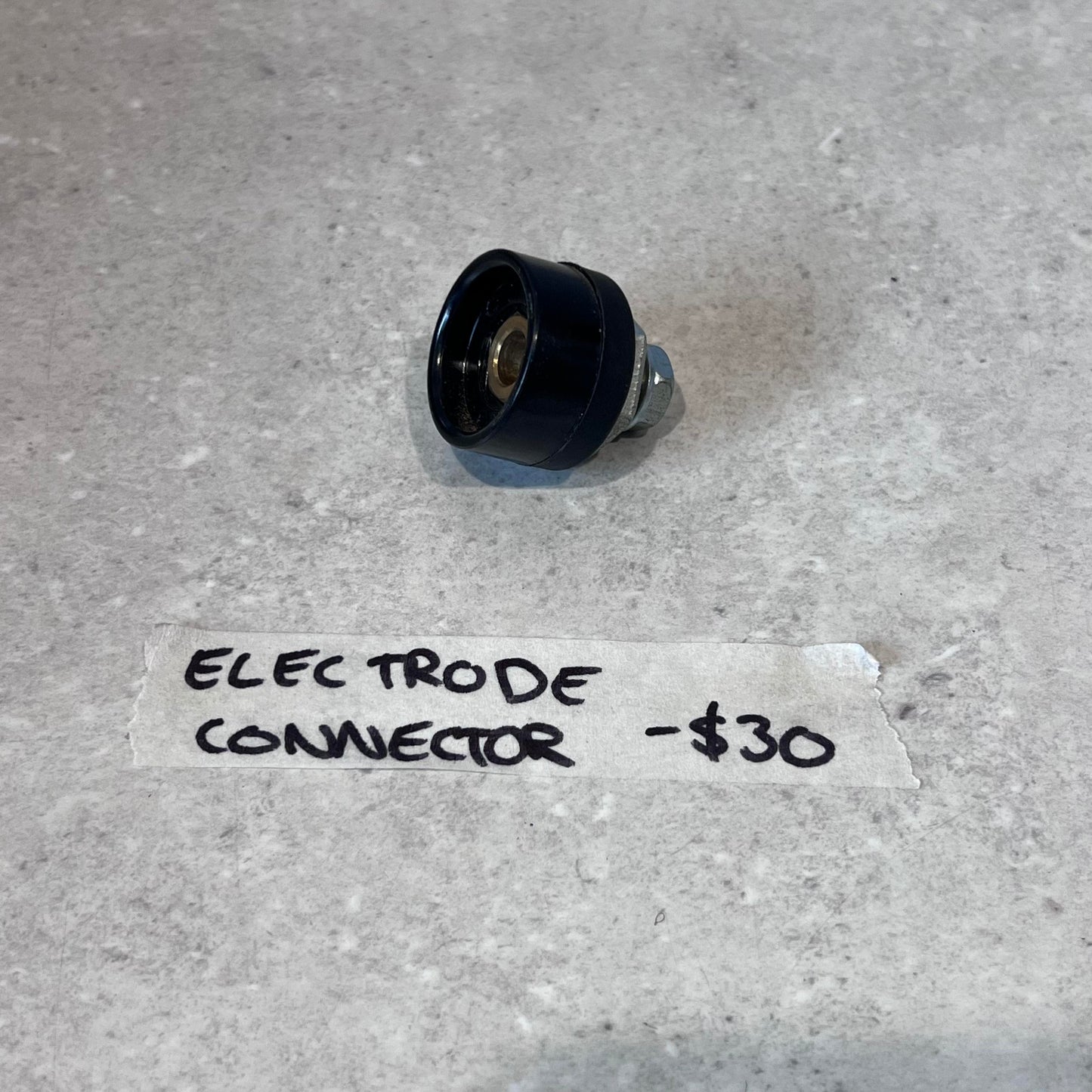 Electrode connector for CUT50 plasma cutter on a light surface with handwritten label and price