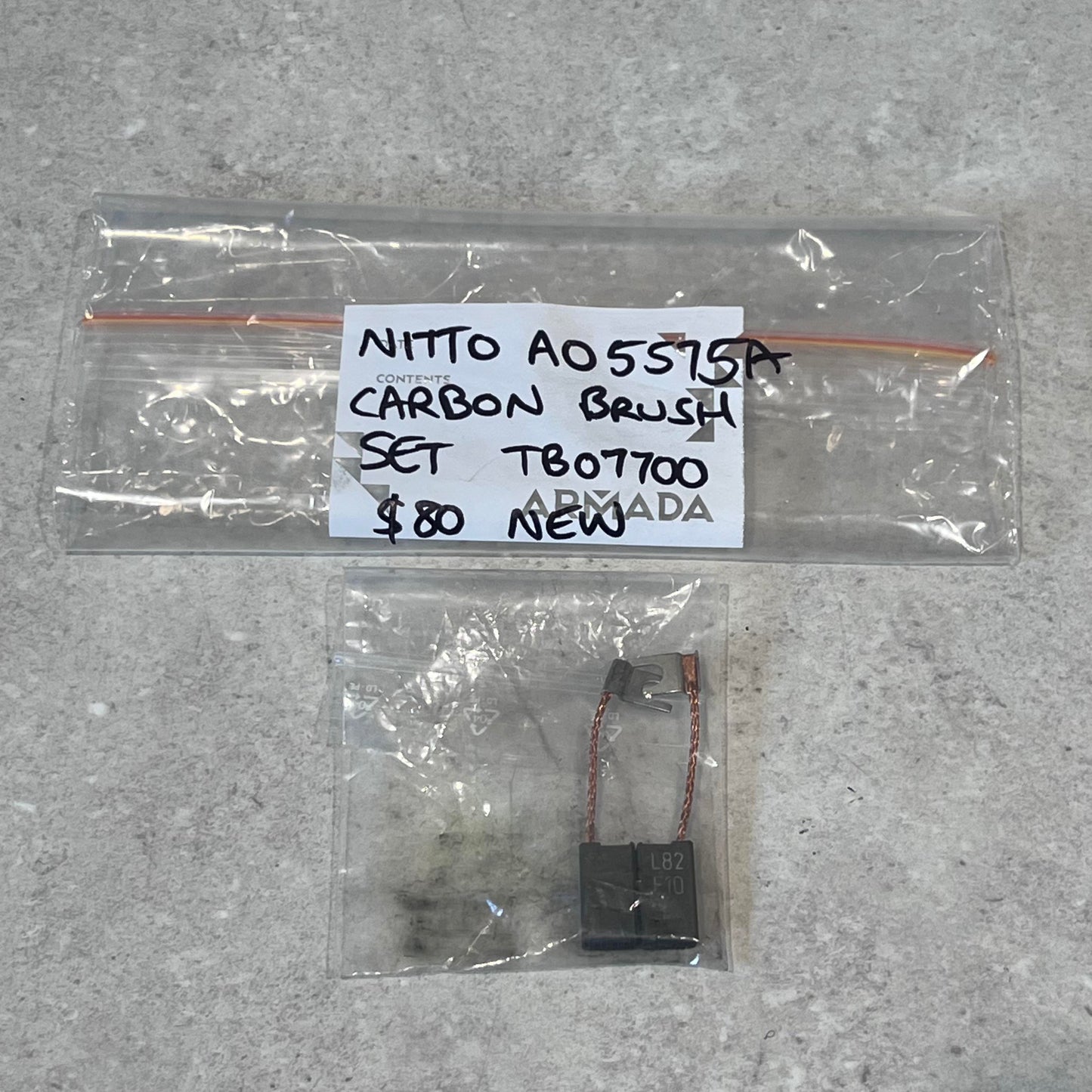 Nitto A05575A carbon brush set TB07700 in clear packaging on gray surface
