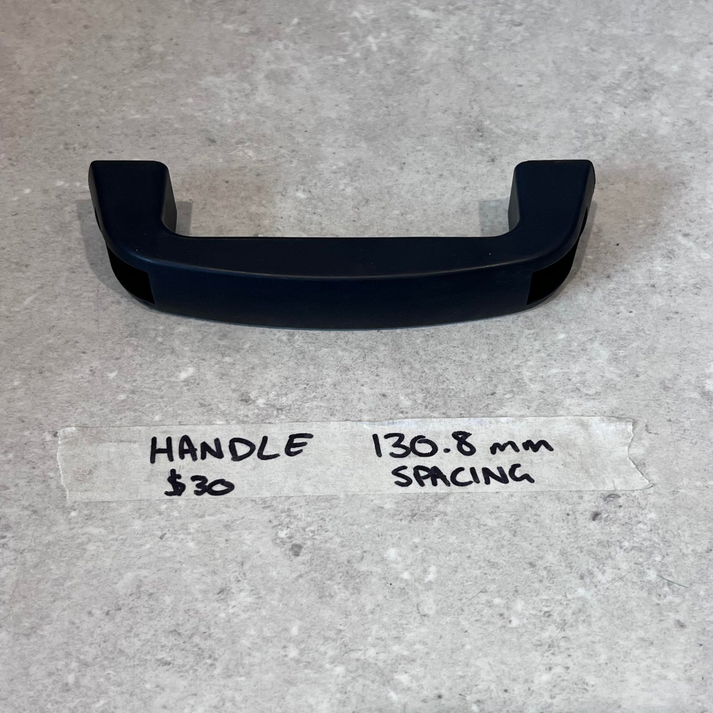 Black replacement handle for CUT50 plasma cutter with 130.8 mm mounting spacing displayed on a gray surface