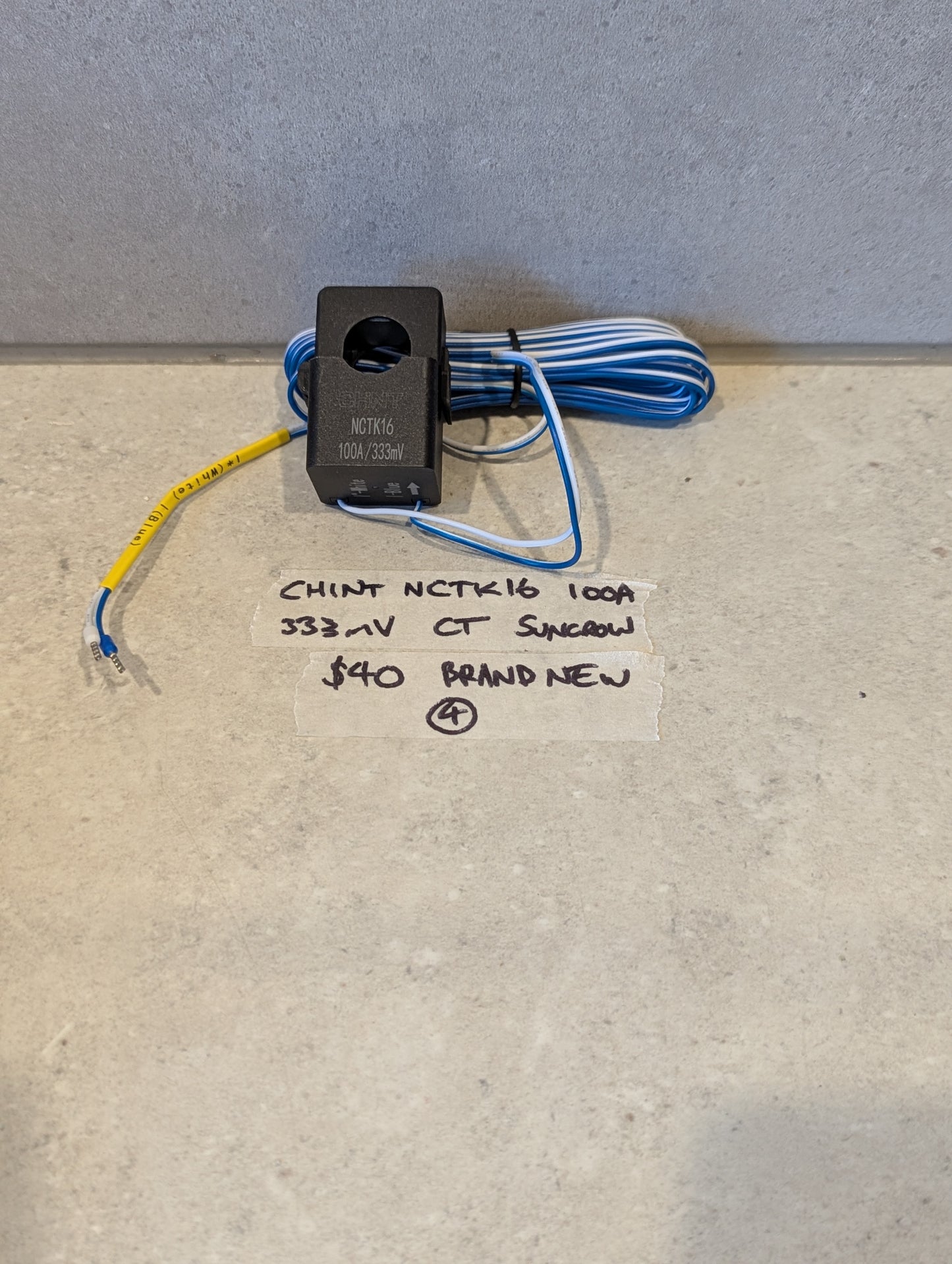 CHINT NCTK16 100A 333mV Current Transformer with blue and white wiring on a light surface
