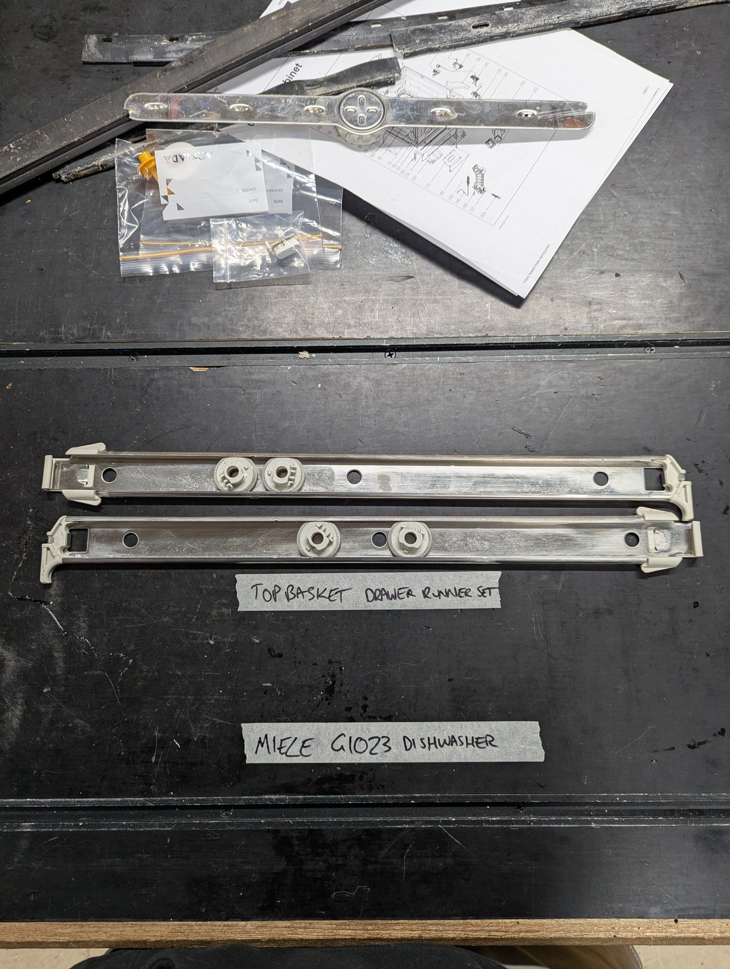 Miele G1023 dishwasher top basket drawer runner set laid out on a table with installation hardware and instructions.
