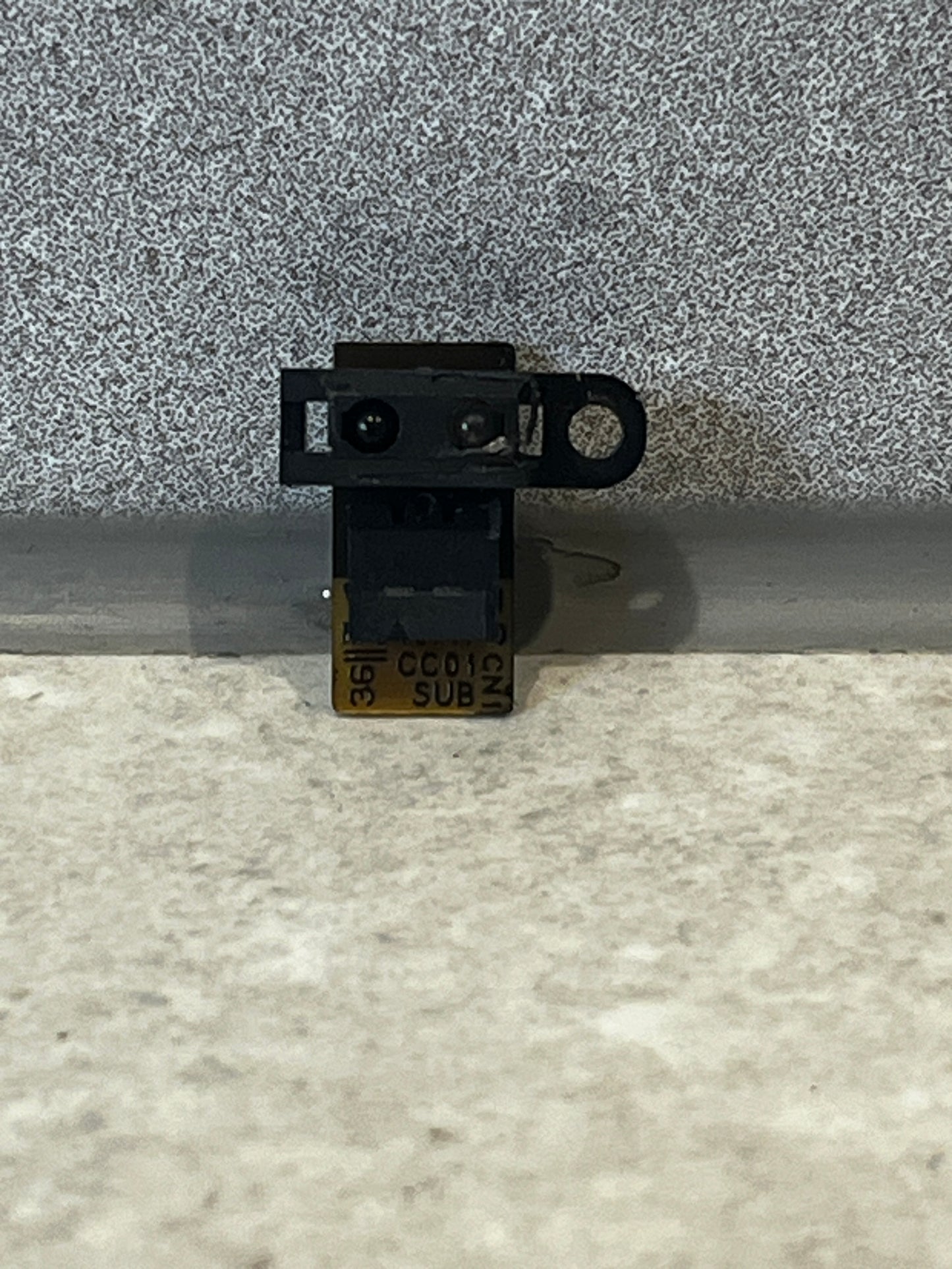 Close-up of a small black infrared camera module with a flexible circuit board for laptops