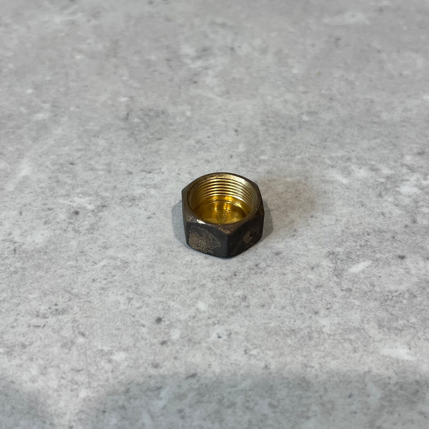 Brass 1/4 inch service valve cap on gray surface