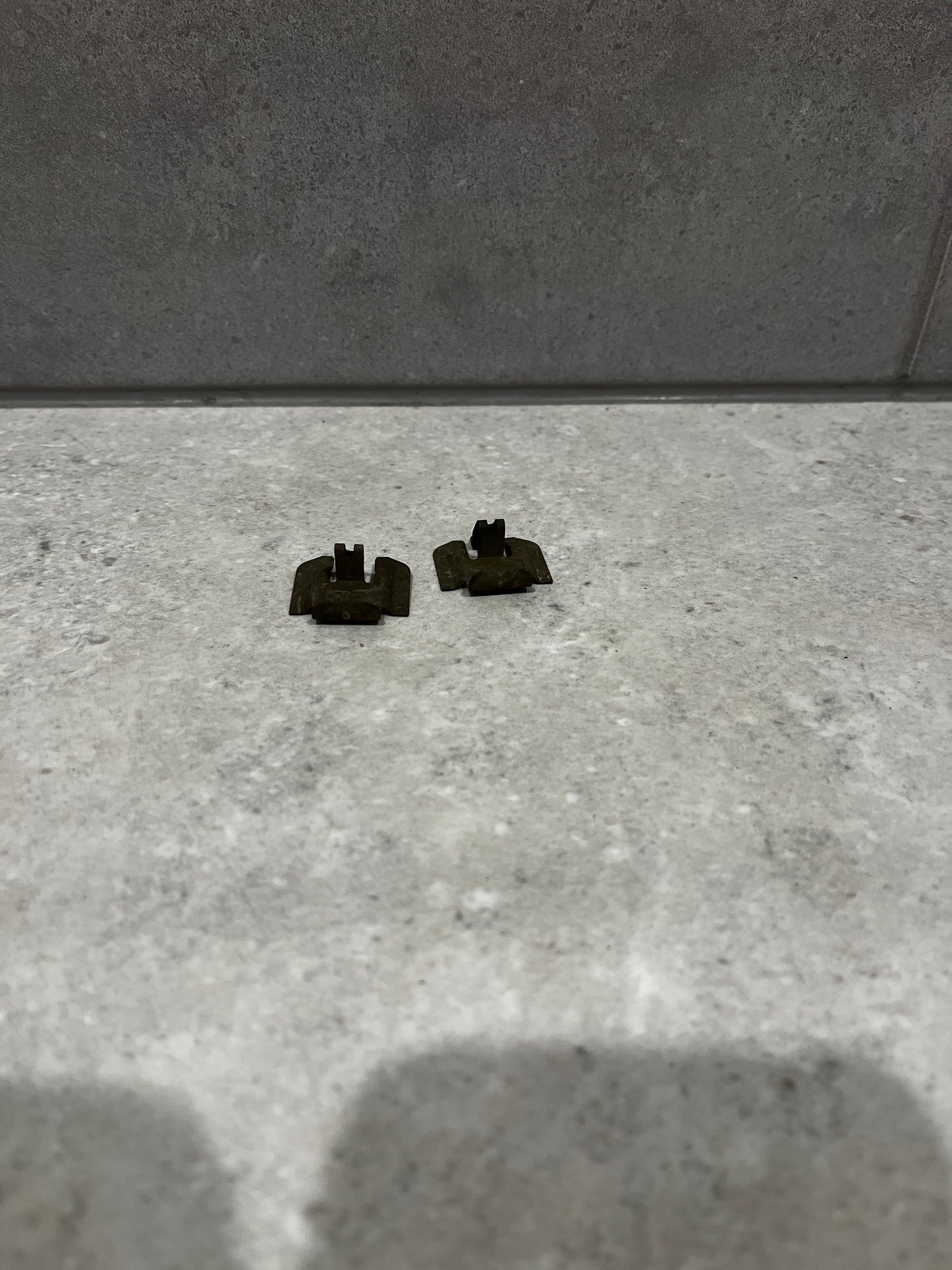 Pair of small metal clip fasteners on stone surface