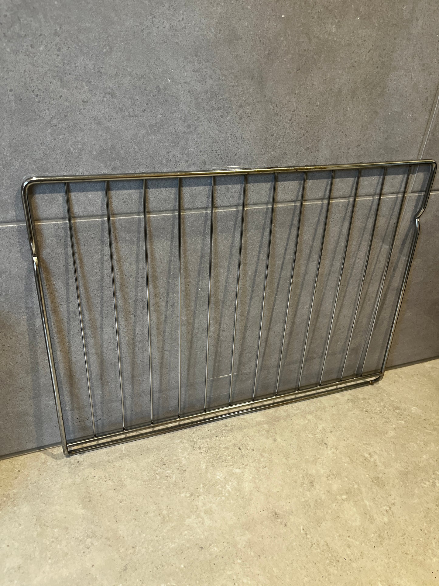 stainless steel oven rack resting against kitchen wall
