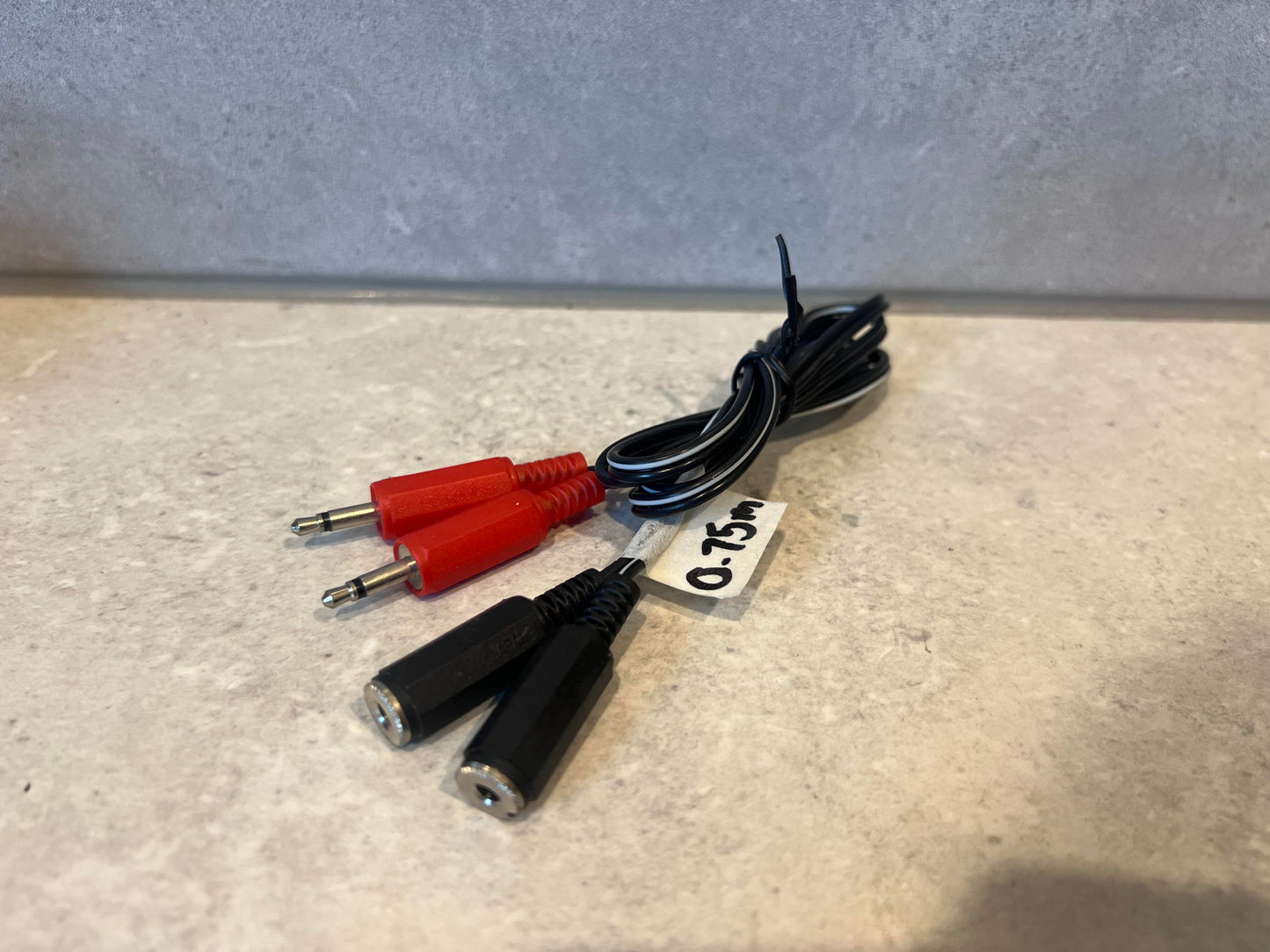 Dual 3.5mm mono jack splitter cable with red and black connectors and 0.75m label