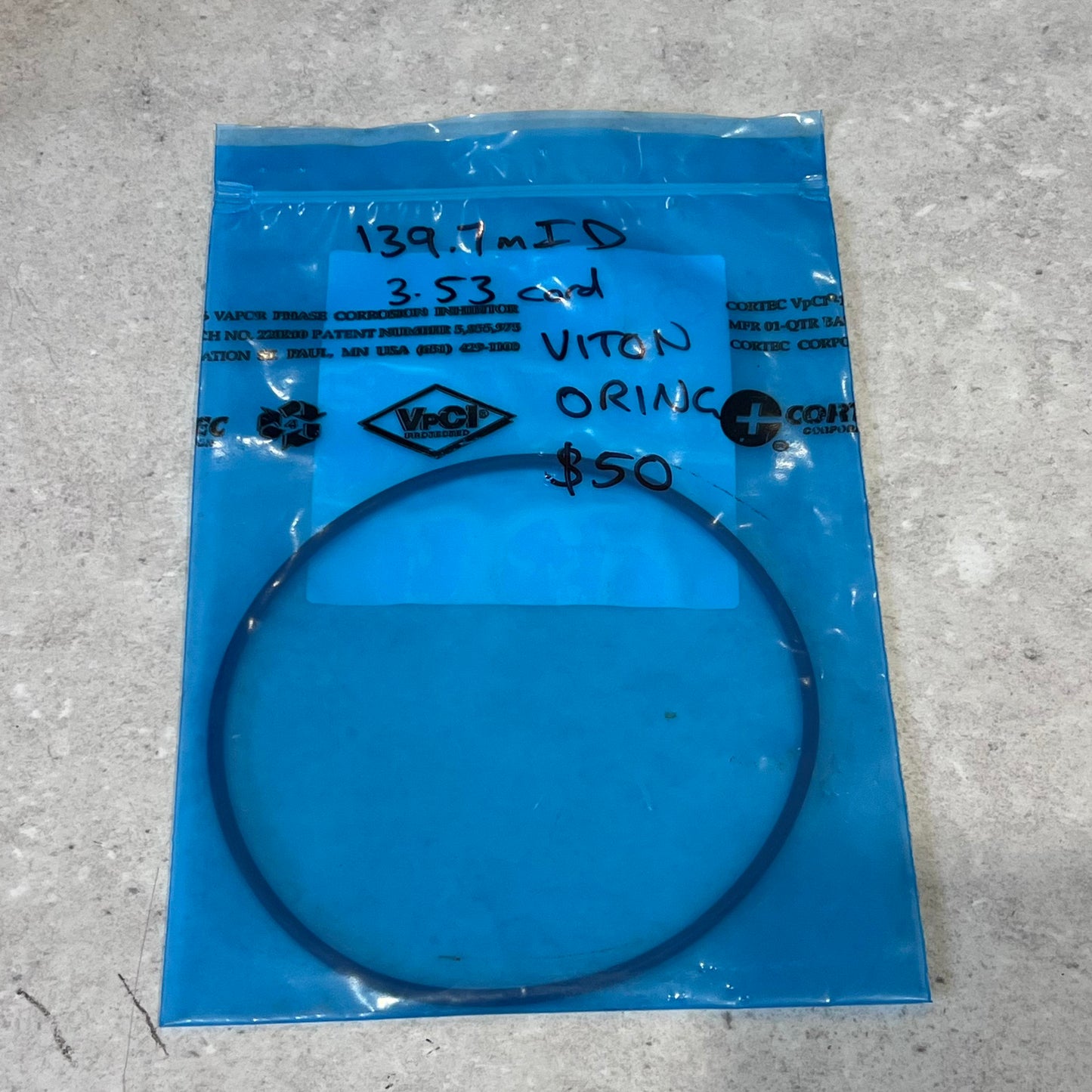 Viton O-ring with 139.7mm ID in blue VpCI packaging on gray surface