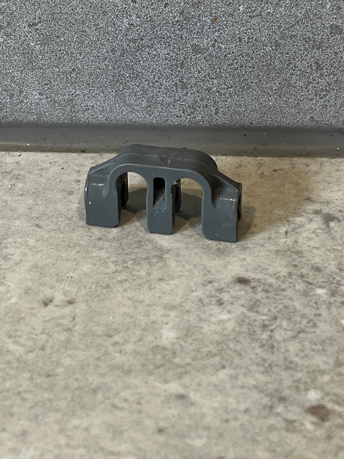 Gray plastic pipe support bracket on concrete surface