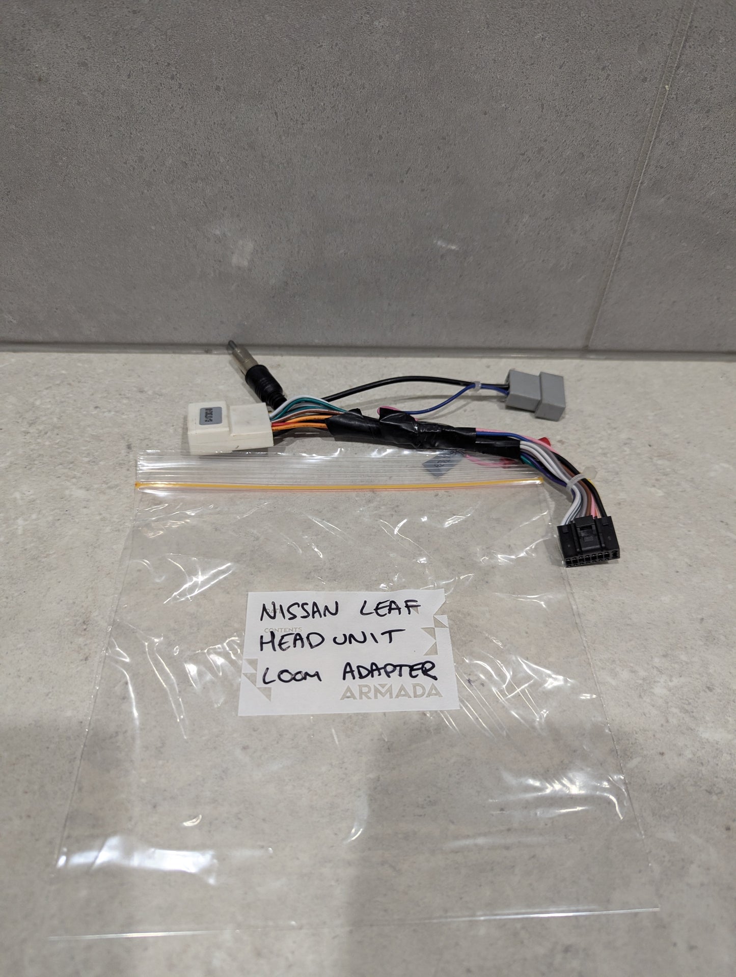 Nissan Leaf head unit loom adapter wiring harness on a countertop with labeled bag