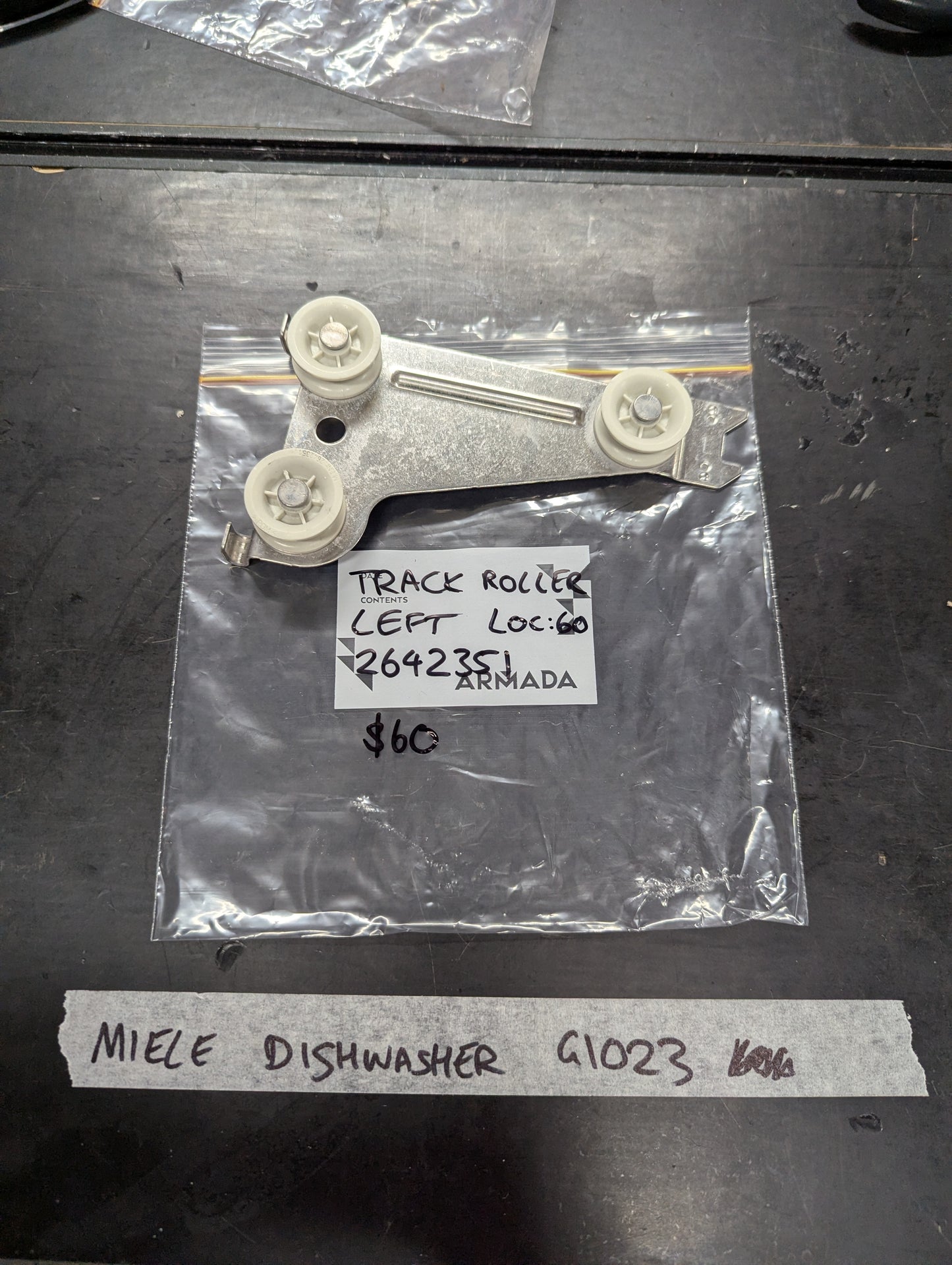 Miele G1023 dishwasher left track roller assembly on black surface
