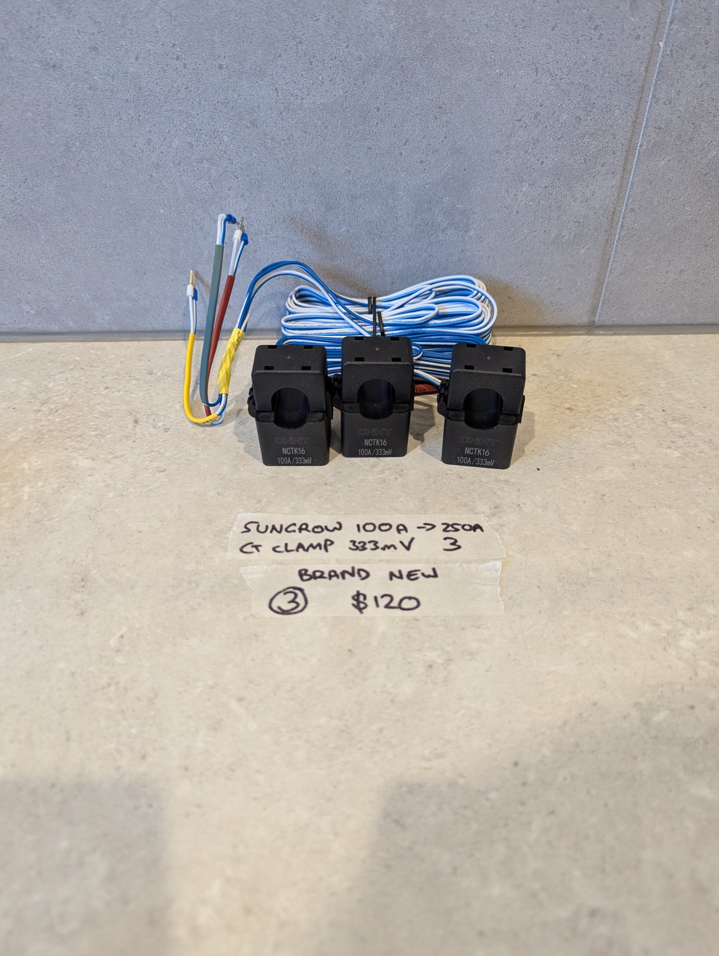 Set of three Sungrow MCTK16 CT clamps with attached wires on a light surface
