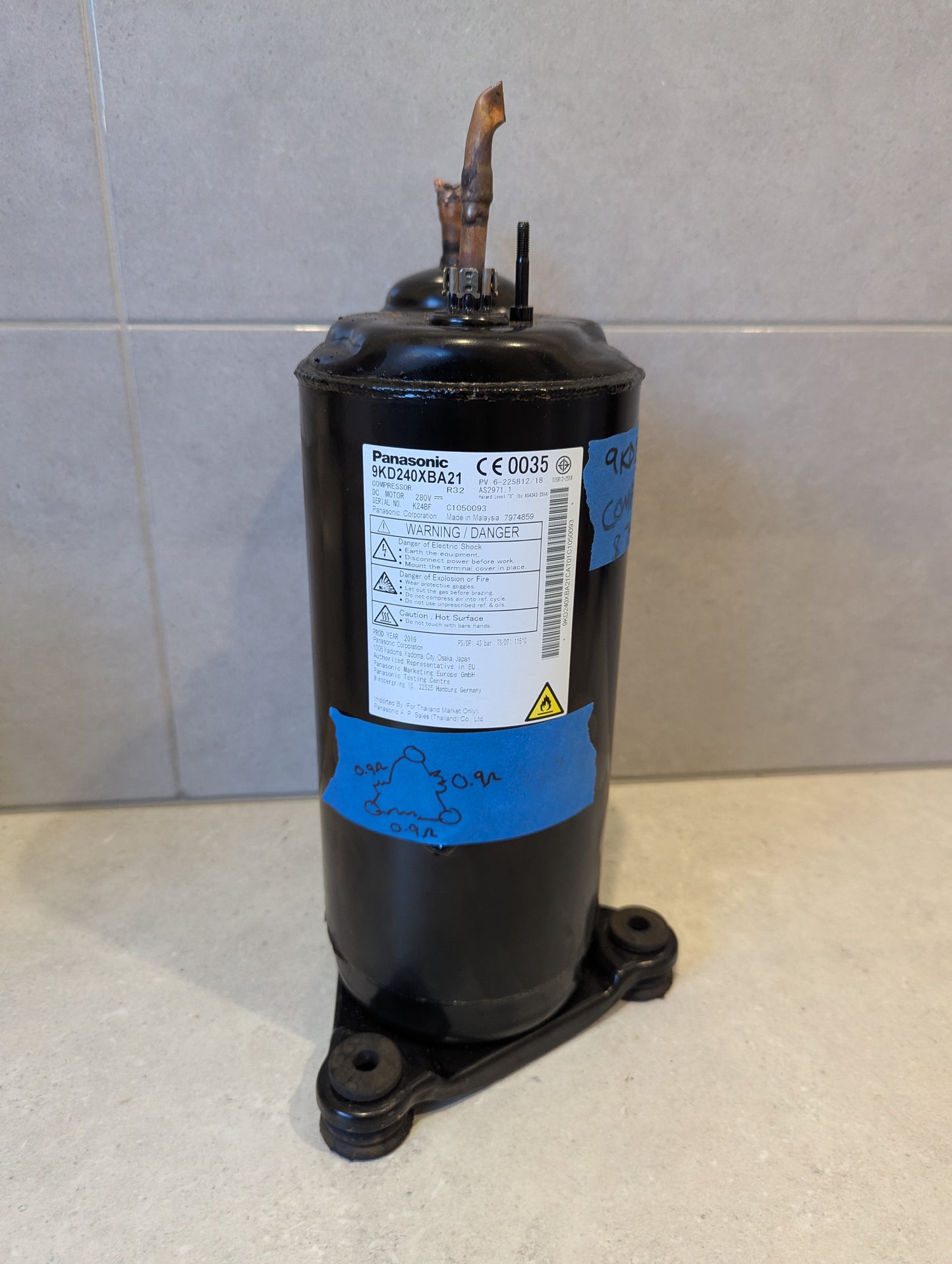 Panasonic 9KD240XBA21 air conditioner compressor with product label and blue tape markings
