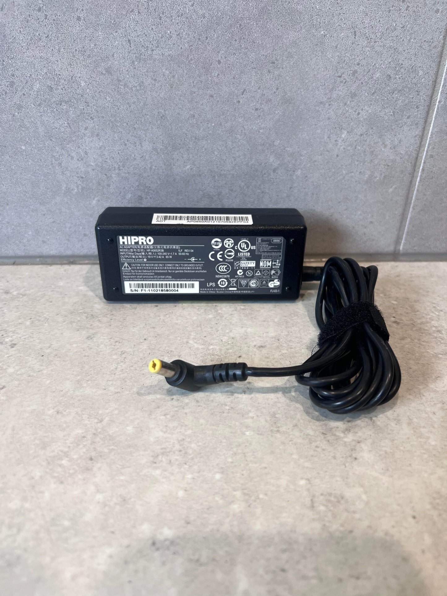 HIPRO laptop power adapter with attached cord and plug on a stone surface
