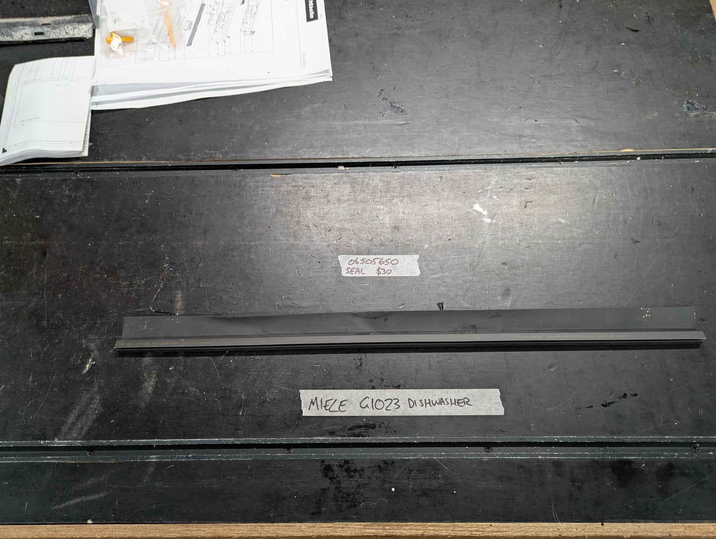 Miele G1023 dishwasher black rubber door seal on workbench with label