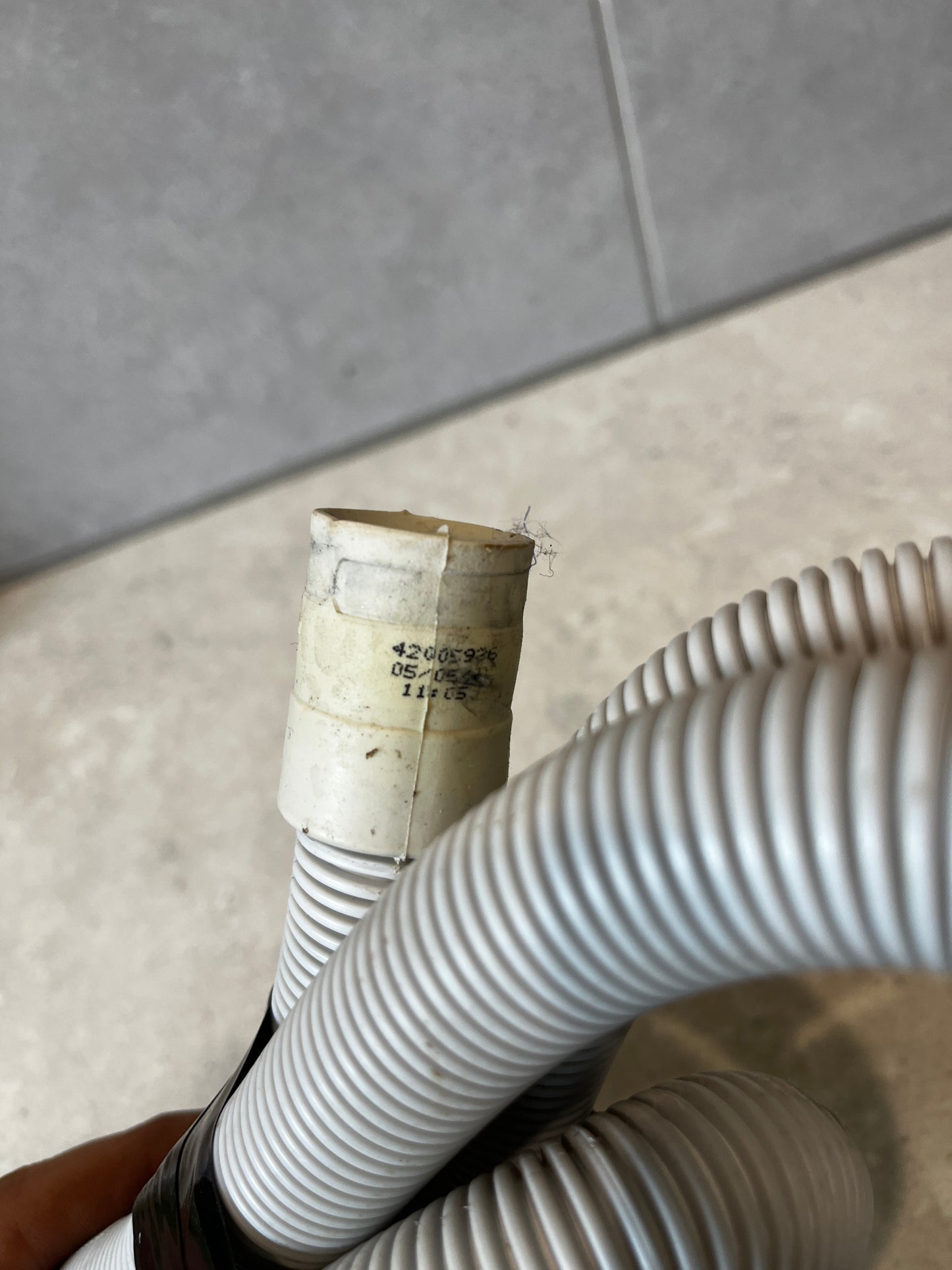 Close-up of the plastic drain hose connector with printed codes
