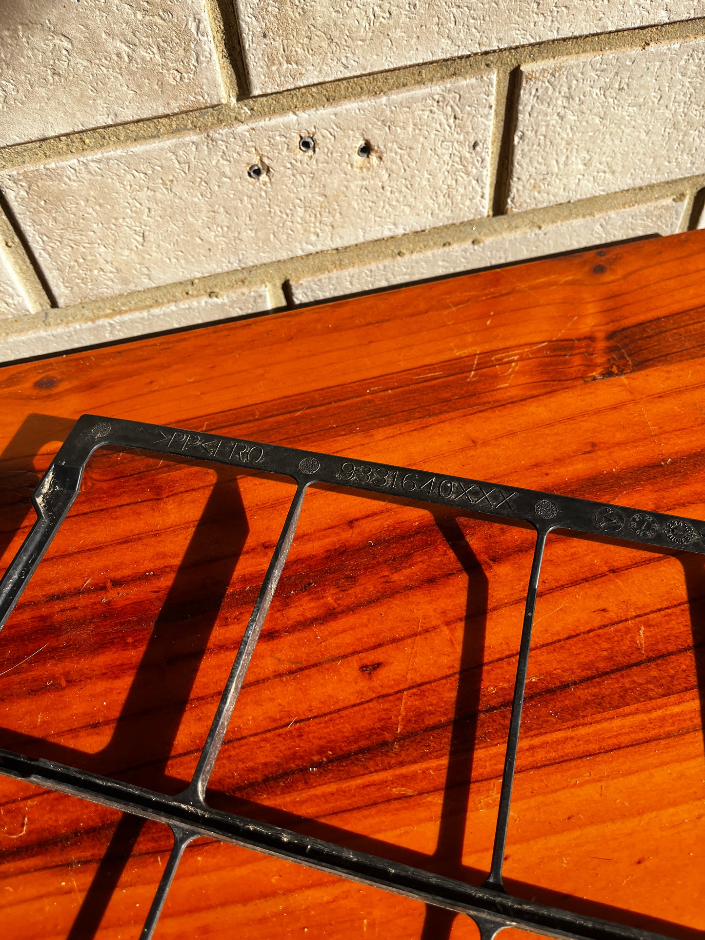 Close-up of black plastic grill grate and grid pattern on wooden surface