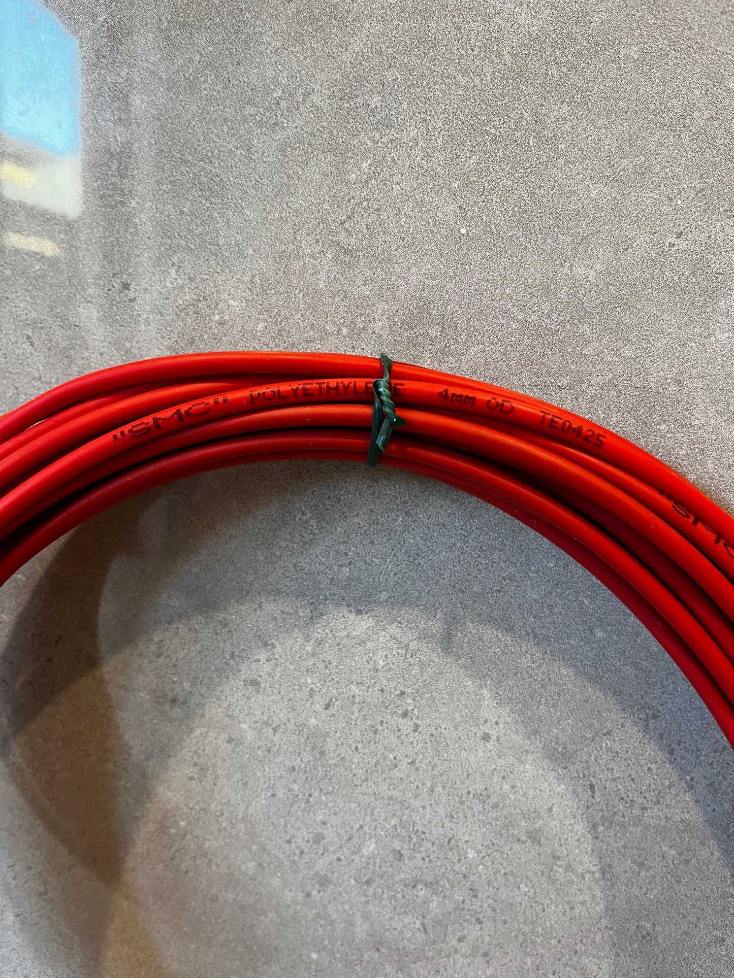 Close-up of red polyethylene tubing with printed text showing 4mm outer diameter