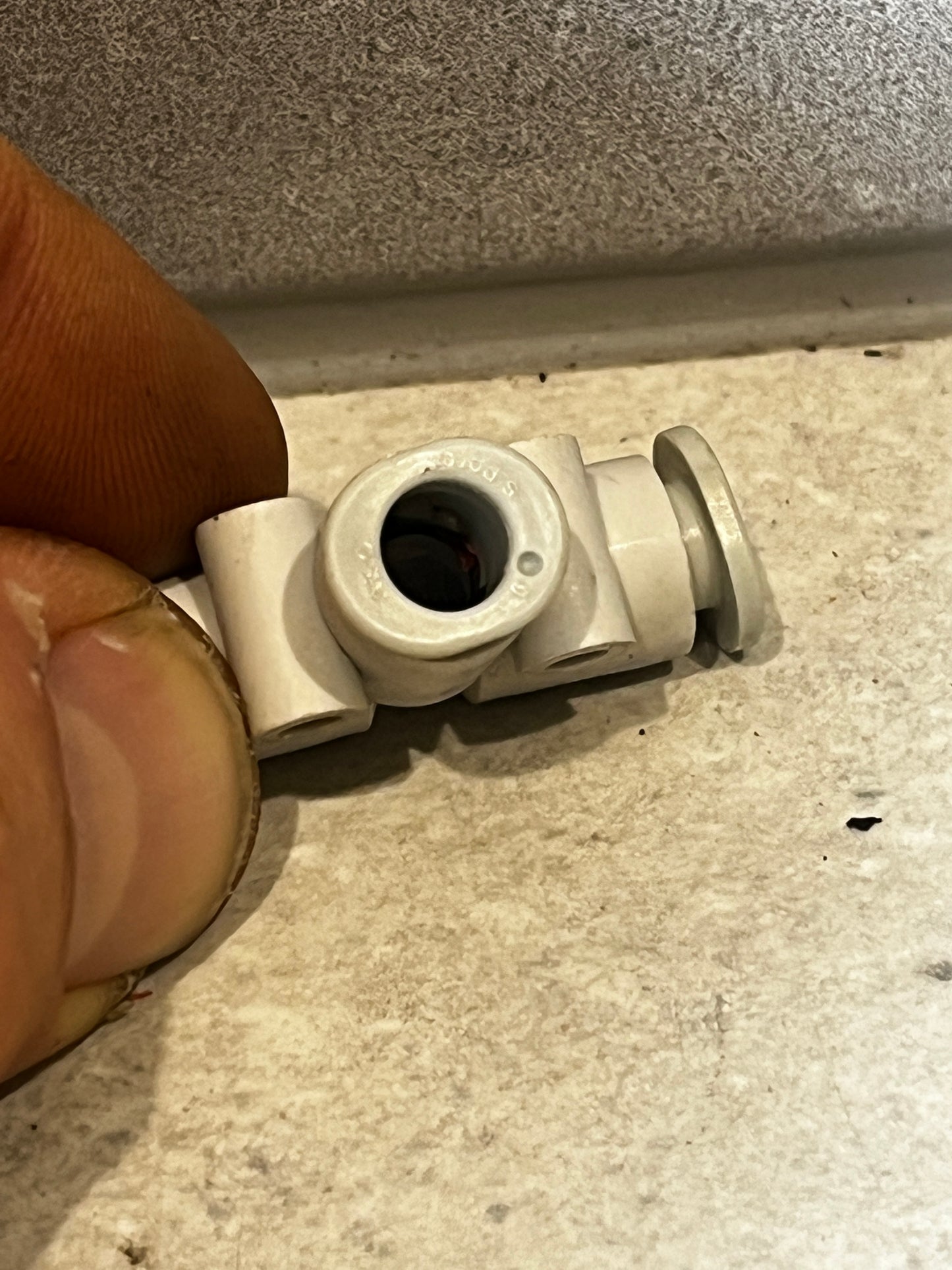 Close-up of plastic pneumatic tube tee fitting connector held by hand