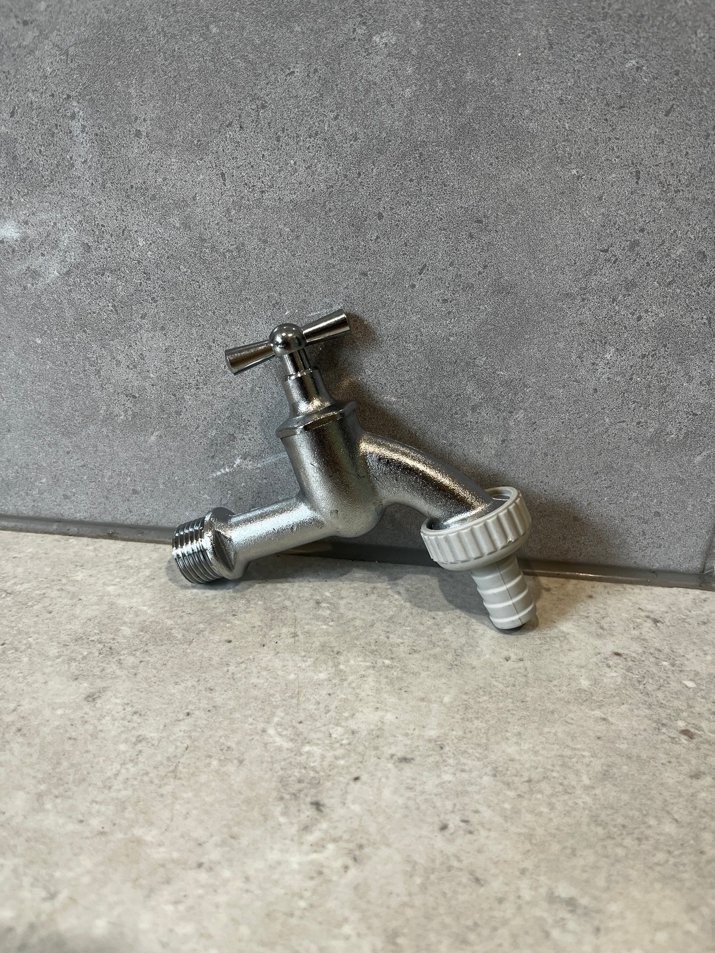 Unboxed stainless steel outdoor water tap with hose connector on stone background