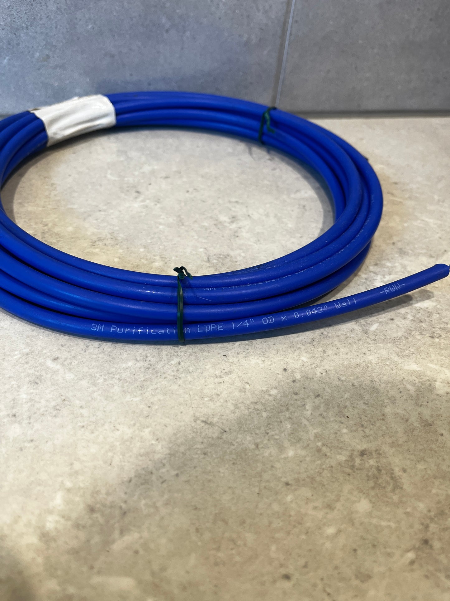 Close-up of blue 3M purification tubing showing 1/4" OD and 0.042" wall thickness specifications.