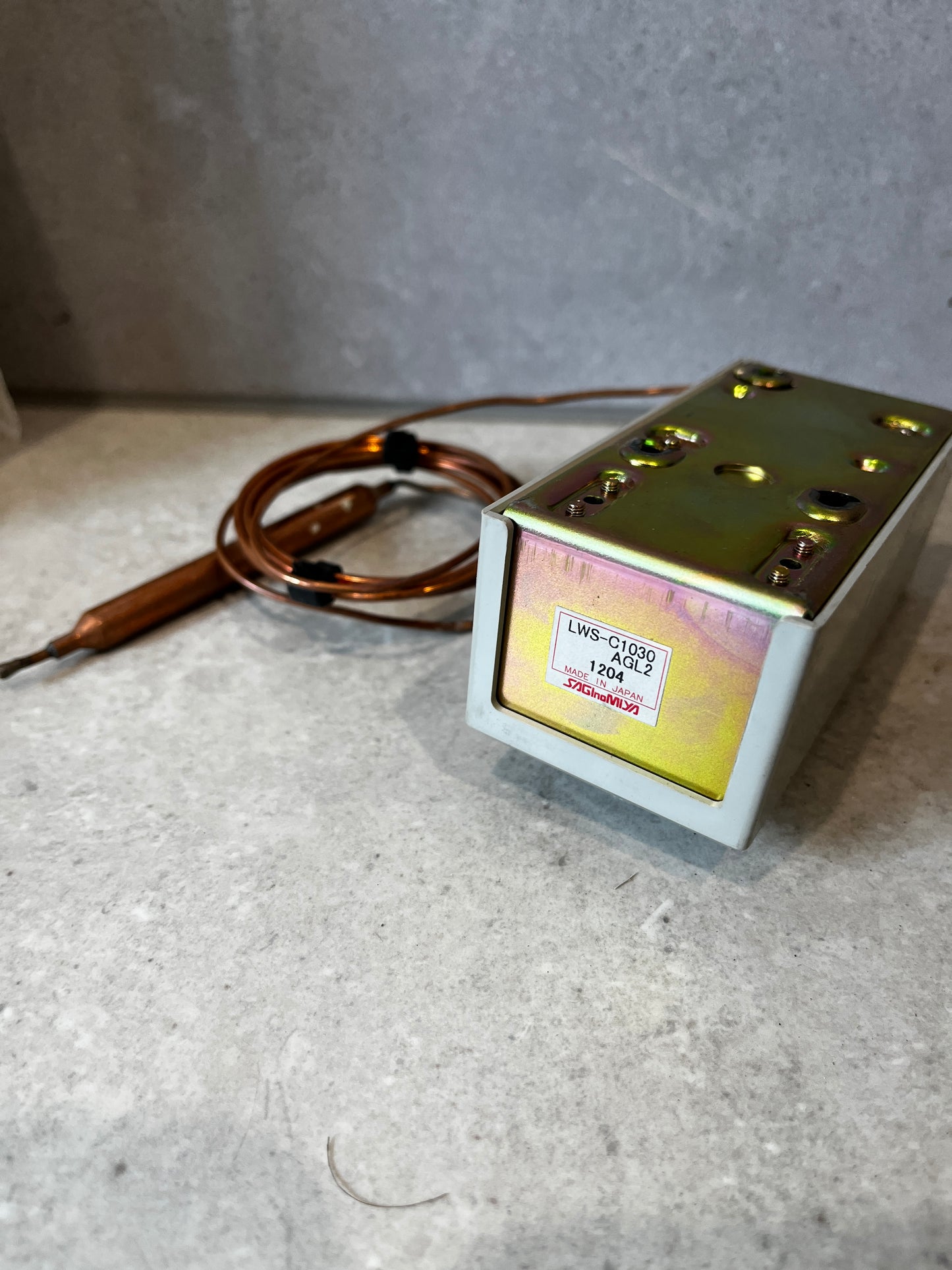 Bottom view of Katronika temperature controller showing mounting plate and label