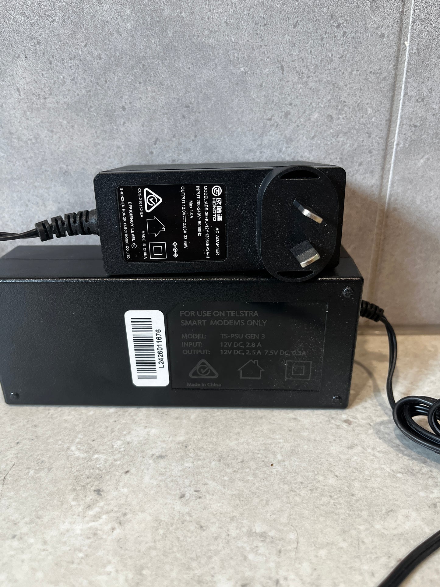 Close-up view of Telstra modem power adapters showing specifications