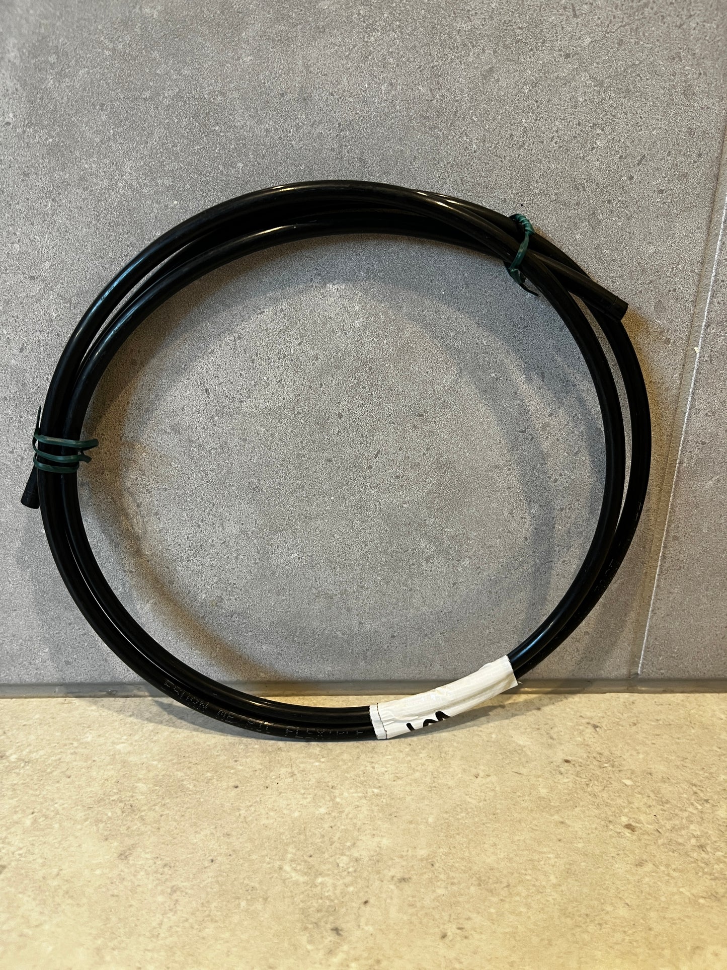 Black flexible tubing coiled with white label marked 1M