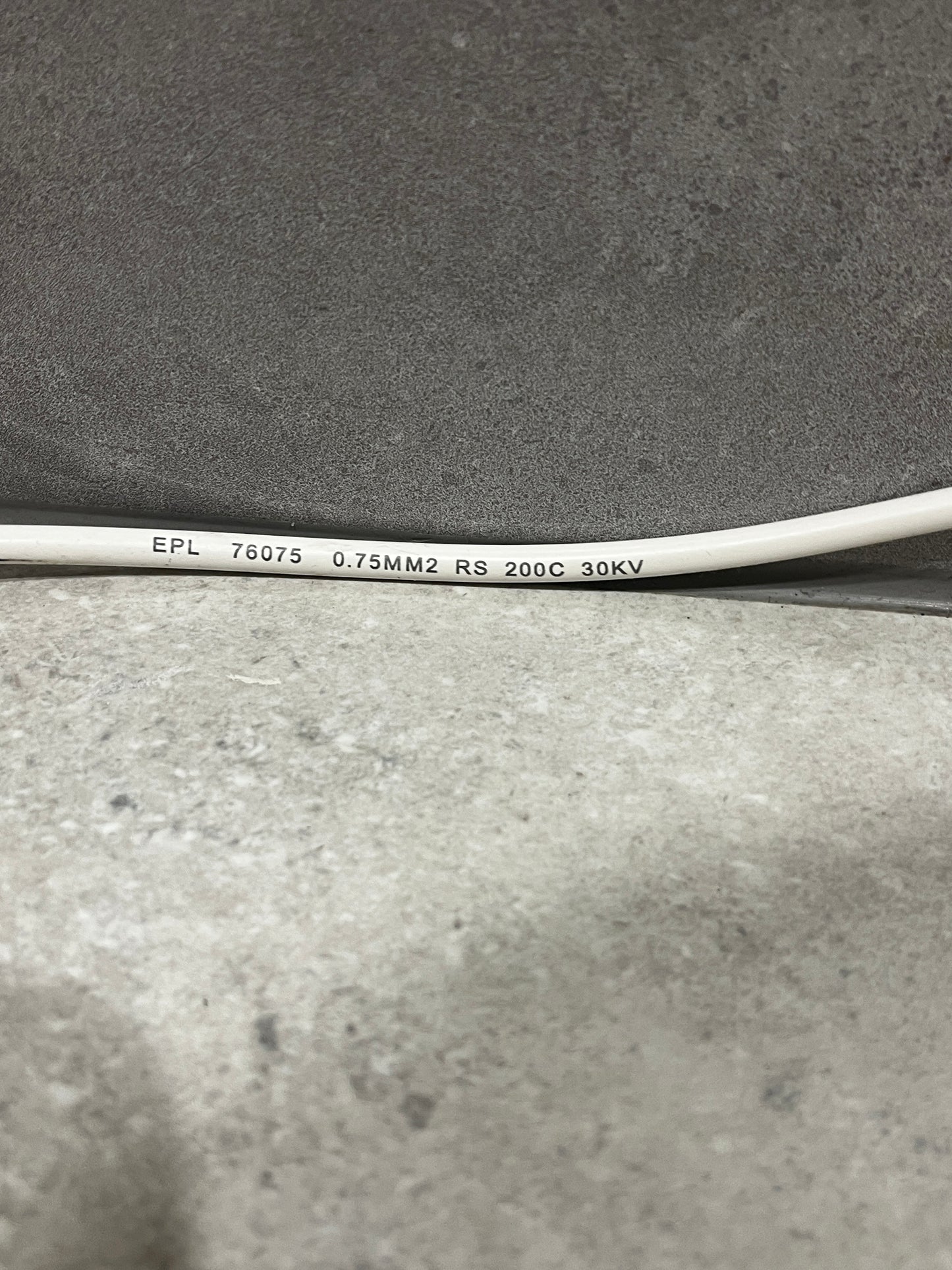 Close-up of white electrical wire showing printed specifications: EPL 76075 0.75MM2 RS 200C 30KV