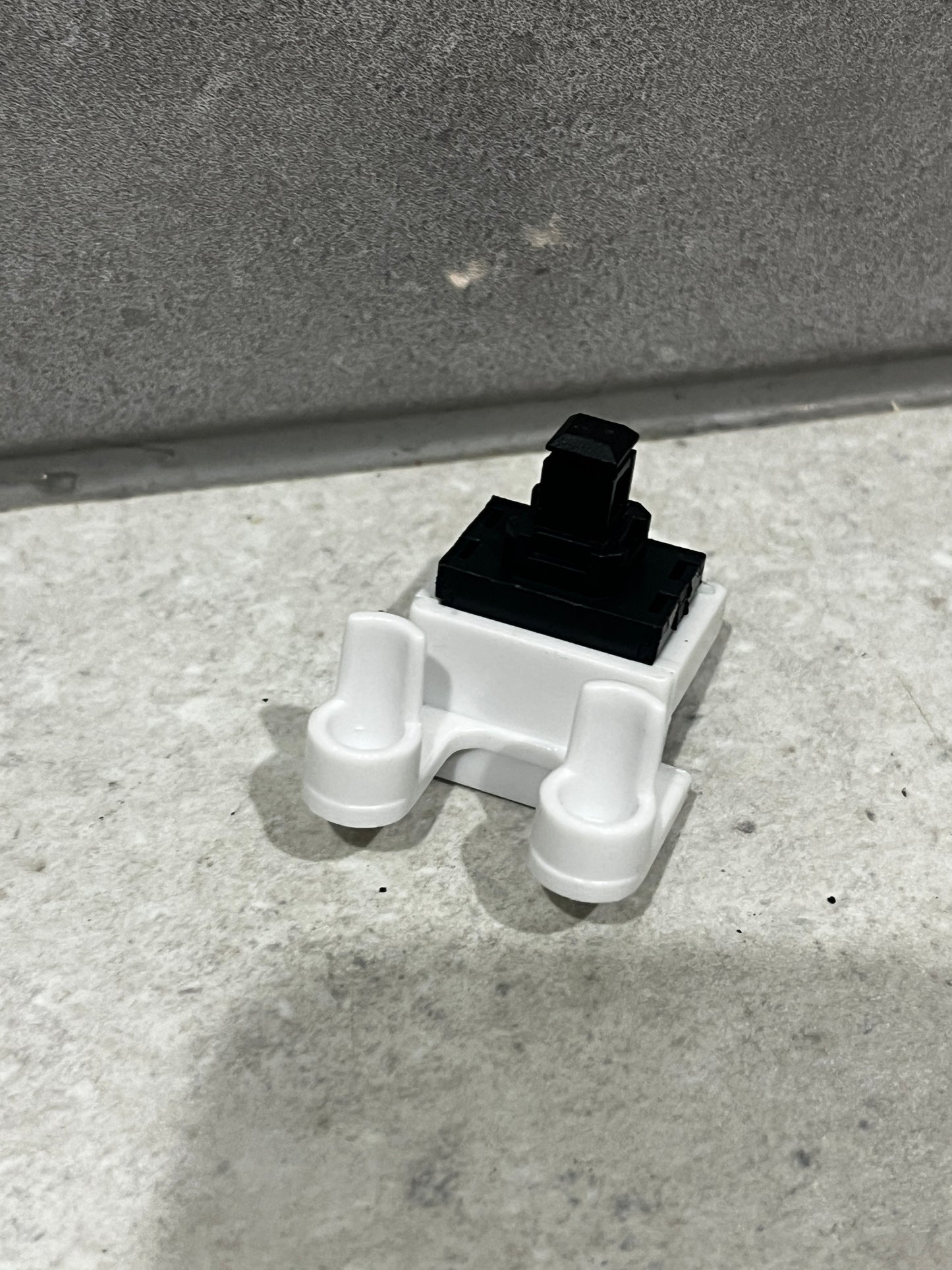 Side angle view of compact push button switch showing actuator and base design