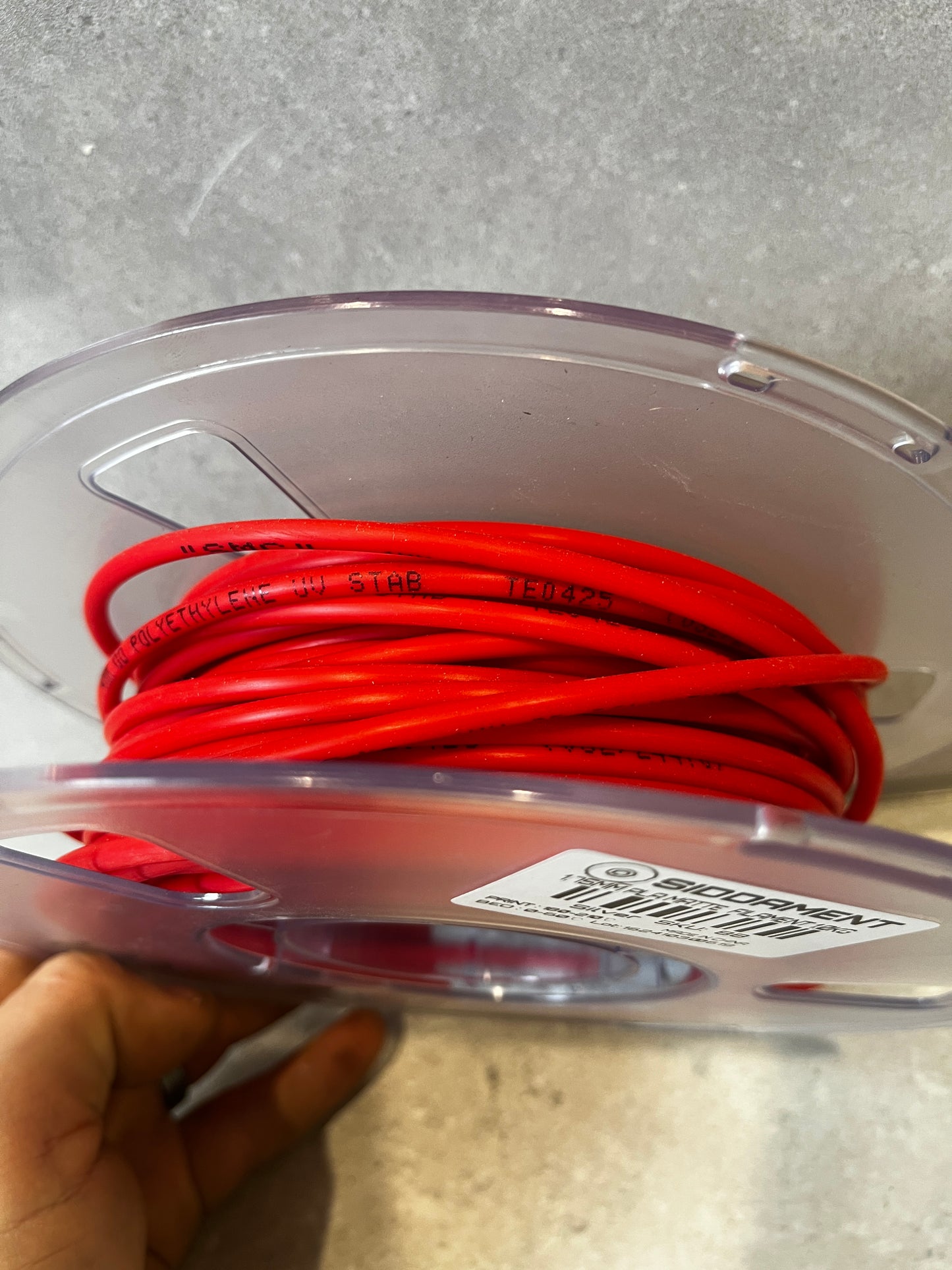 Angled view of red polyethylene tubing spool with visible product labeling