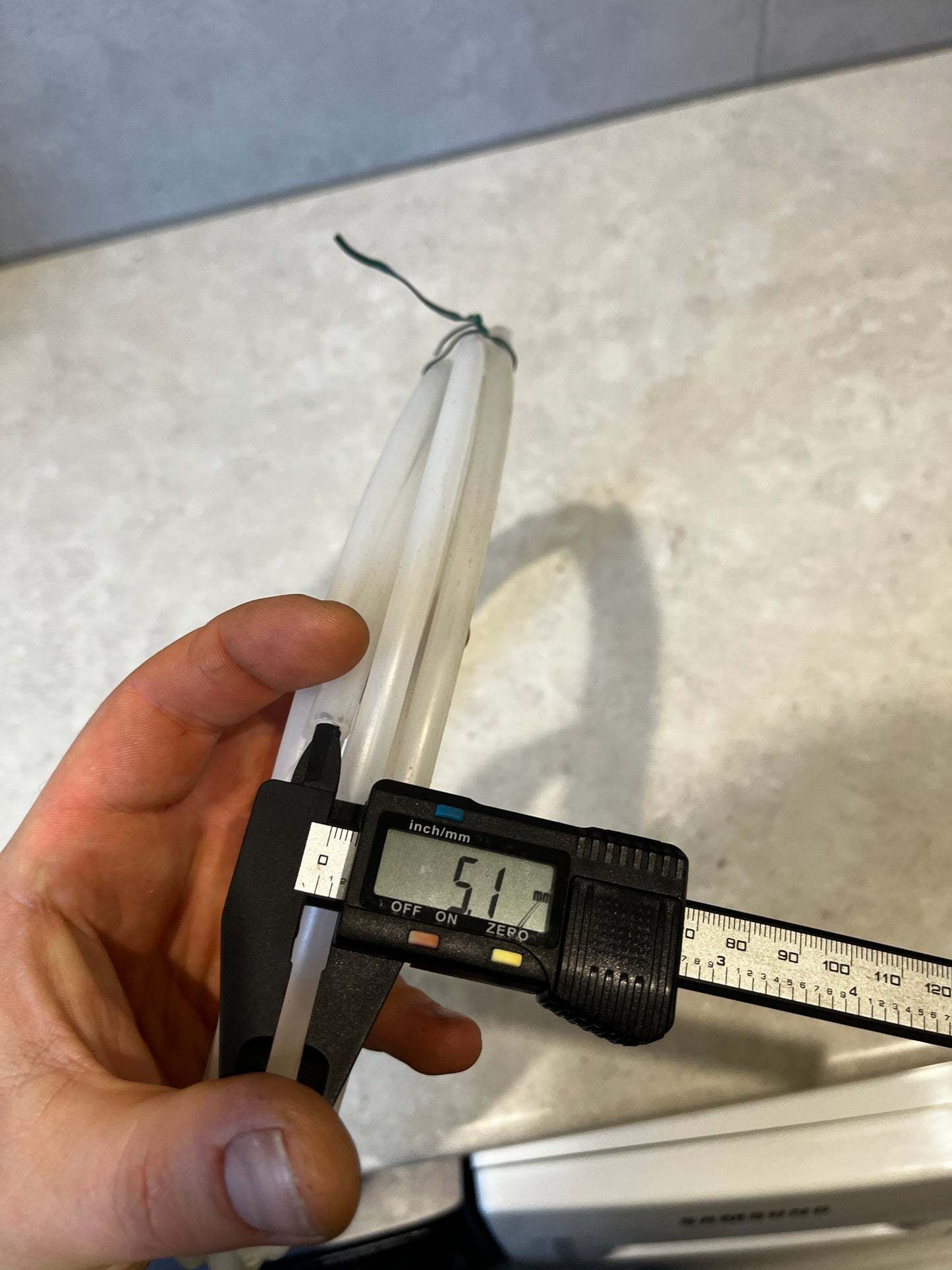 Close-up of digital caliper measuring outer diameter of tubing at 5.1 mm