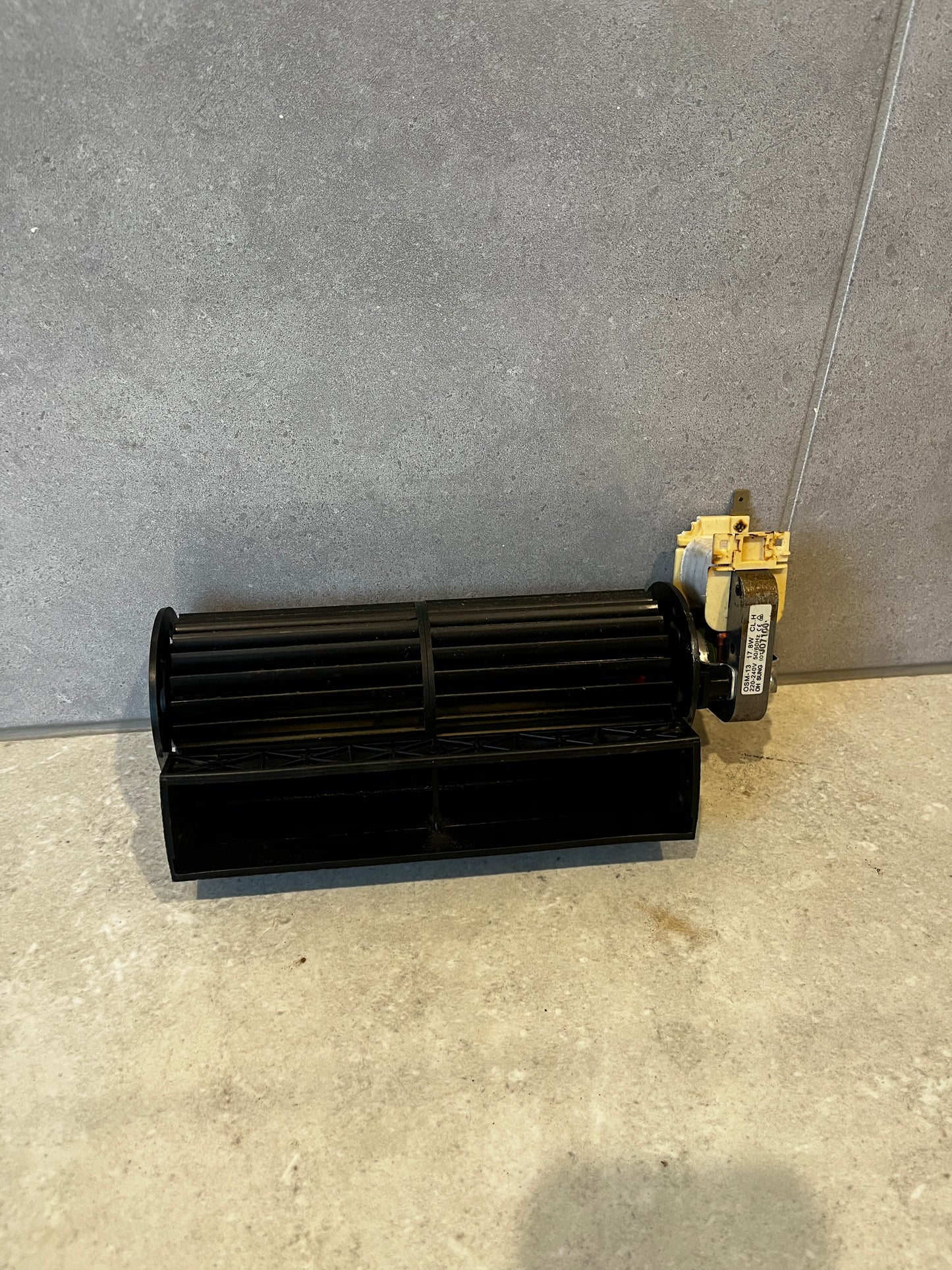 High-power ventilation blower motor with black plastic fan wheel on beige tile background