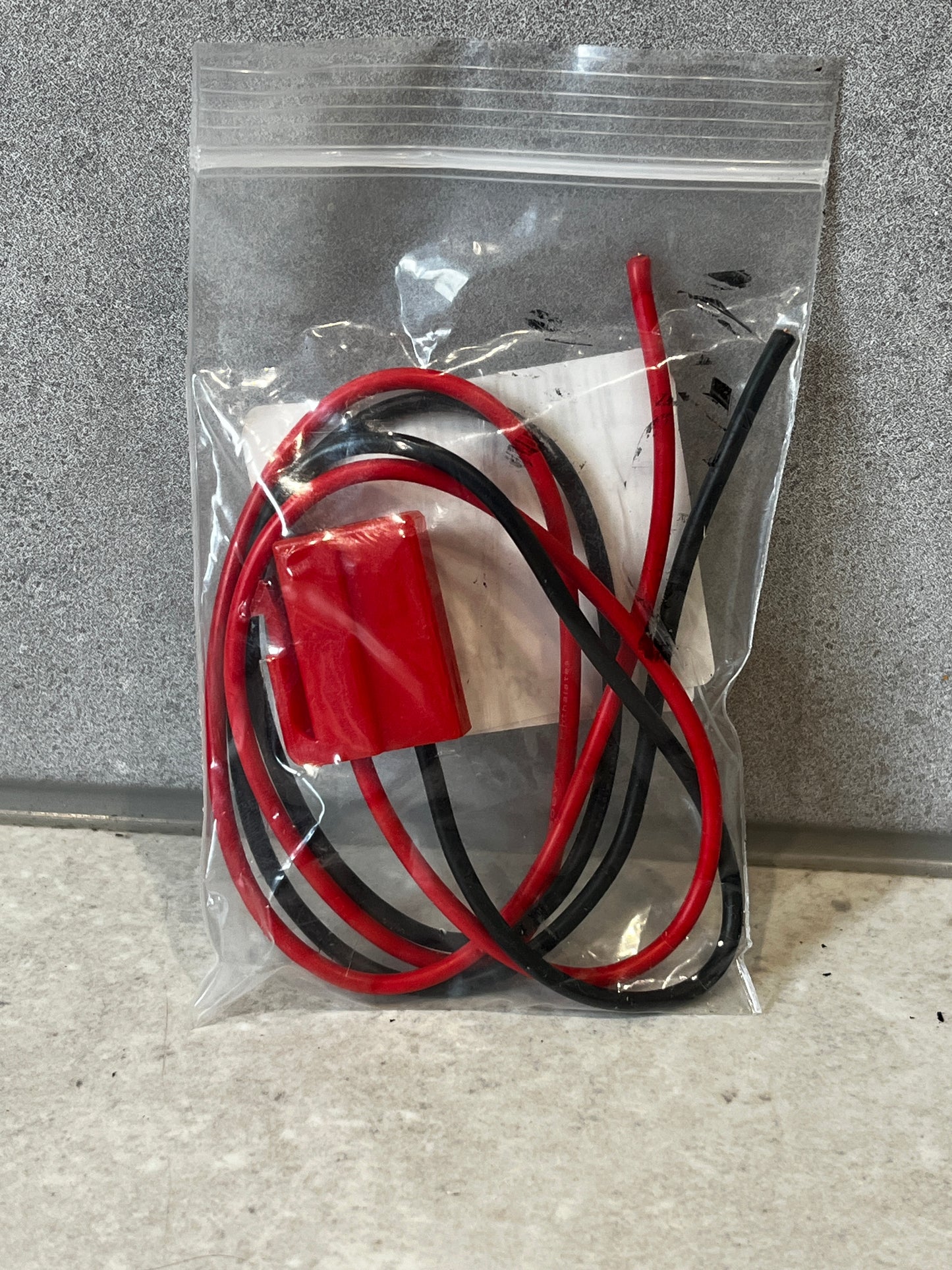 Sealed bag containing red and black insulated wire harness connector
