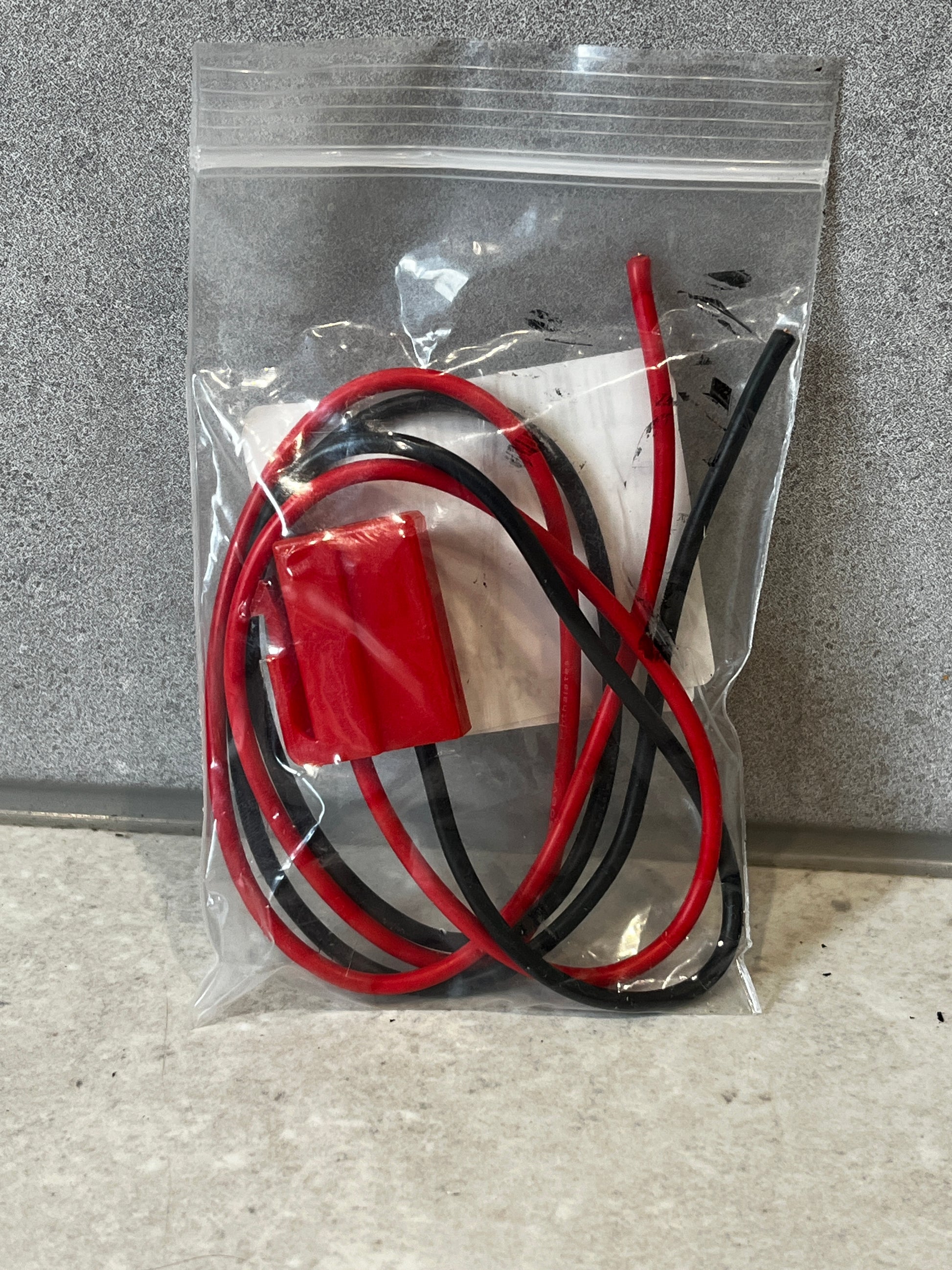 Sealed bag containing red and black insulated wire harness connector