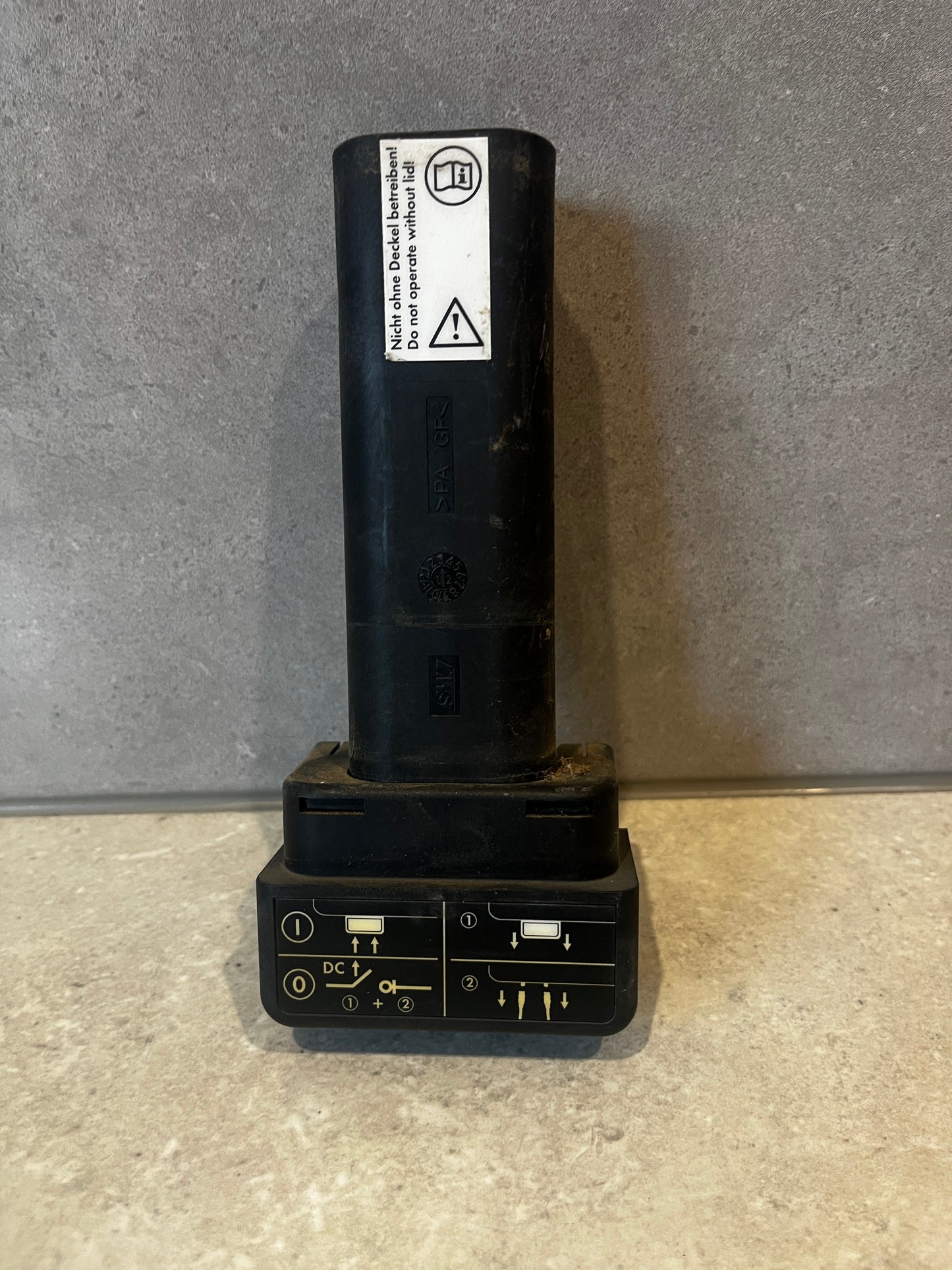 Black plastic electrical connector standing upright with safety instructions on label