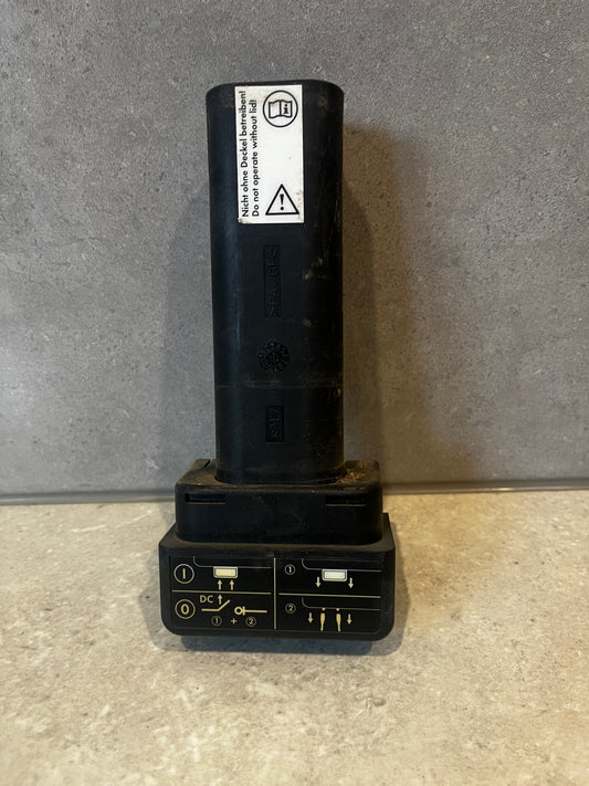 Black plastic electrical connector standing upright with safety instructions on label