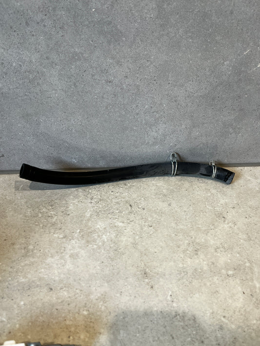 Flexible black rubber hose with metal clamps on a gray surface