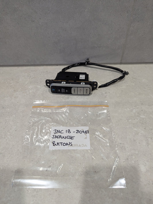 Japanese button automotive control switch panel with wiring on a countertop next to labeled plastic bag