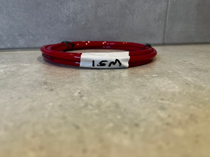 Coiled red polyurethane tubing 1.5 meters length on concrete surface