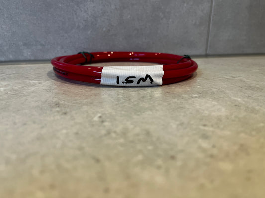 Coiled red polyurethane tubing 1.5 meters length on concrete surface