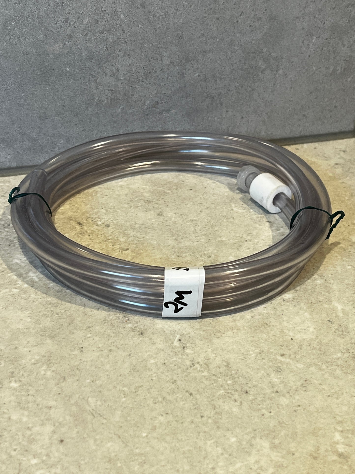 Coiled clear PVC tubing with two fittings on ends placed on countertop