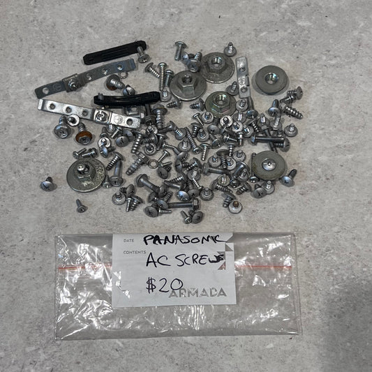 Assorted Panasonic air conditioner screws, washers, brackets, and hardware spread on a surface