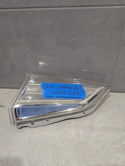 Left side marker light assembly with chrome accents and clear lens on tiled background