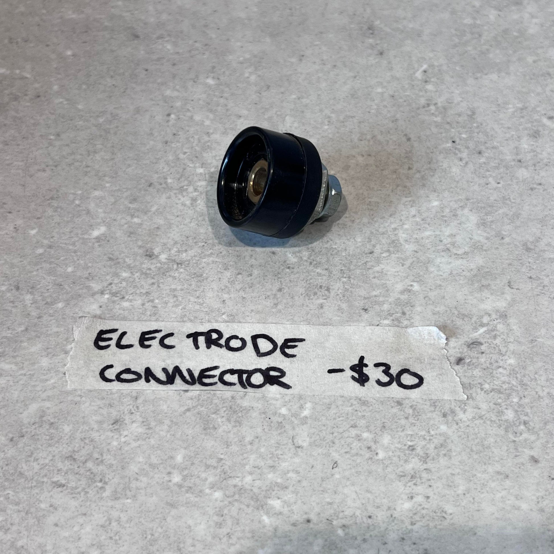 Electrode connector for CUT50 plasma cutter on a light surface with handwritten label and price