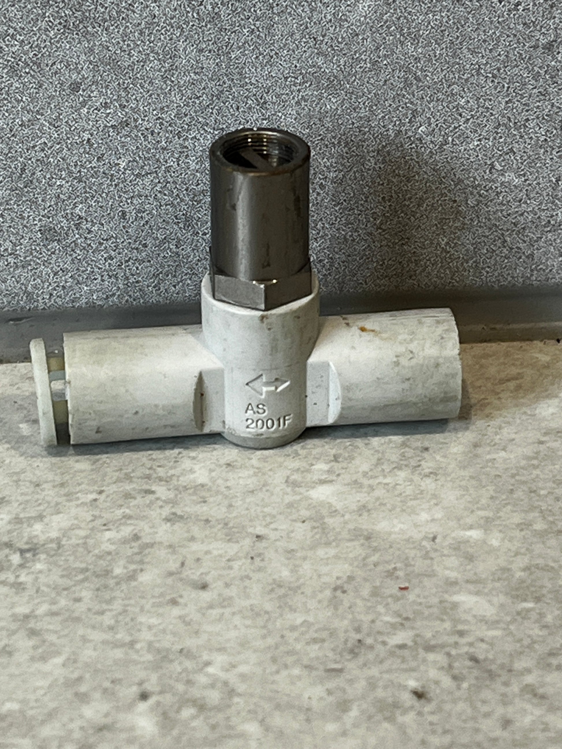 T-shaped pipe fitting with PVC body and metal threaded connector marked AS 2001F