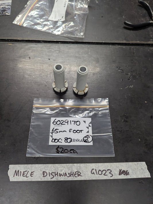 Pair of Miele dishwasher 65mm feet and labeled packaging displayed on a workbench