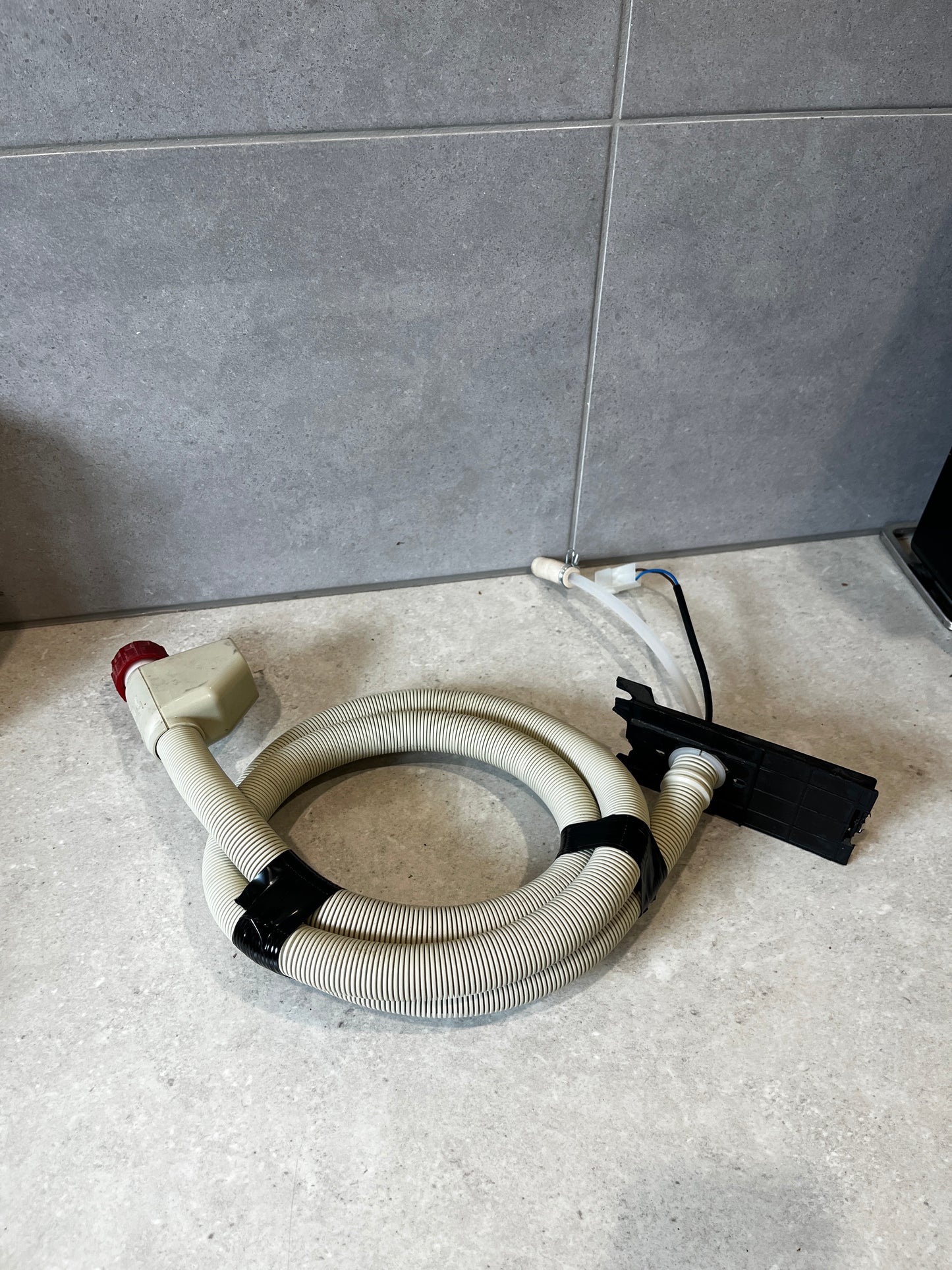 Washing machine inlet hose with electric valve on a tiled surface