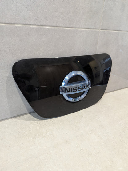 Front view of black Nissan Leaf charging port cover with Nissan logo