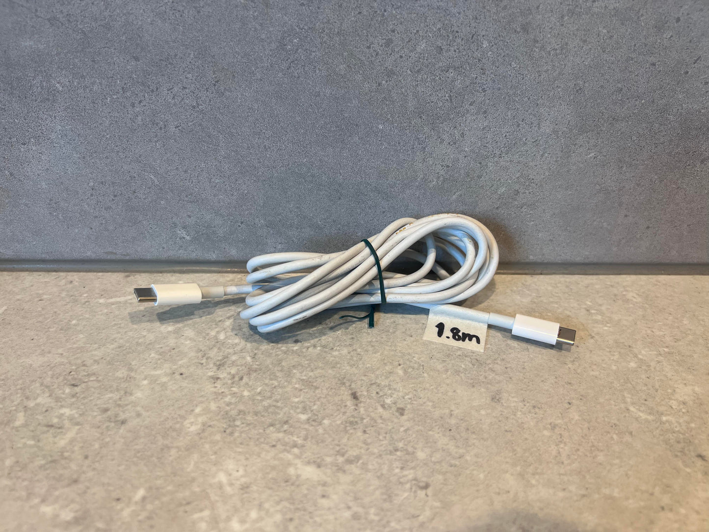 USB-C to USB-C charging cable coiled on a gray surface with 1.8 meter label